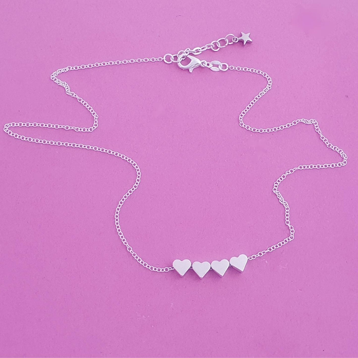 Silver necklace with heart-shaped charms on a purple background