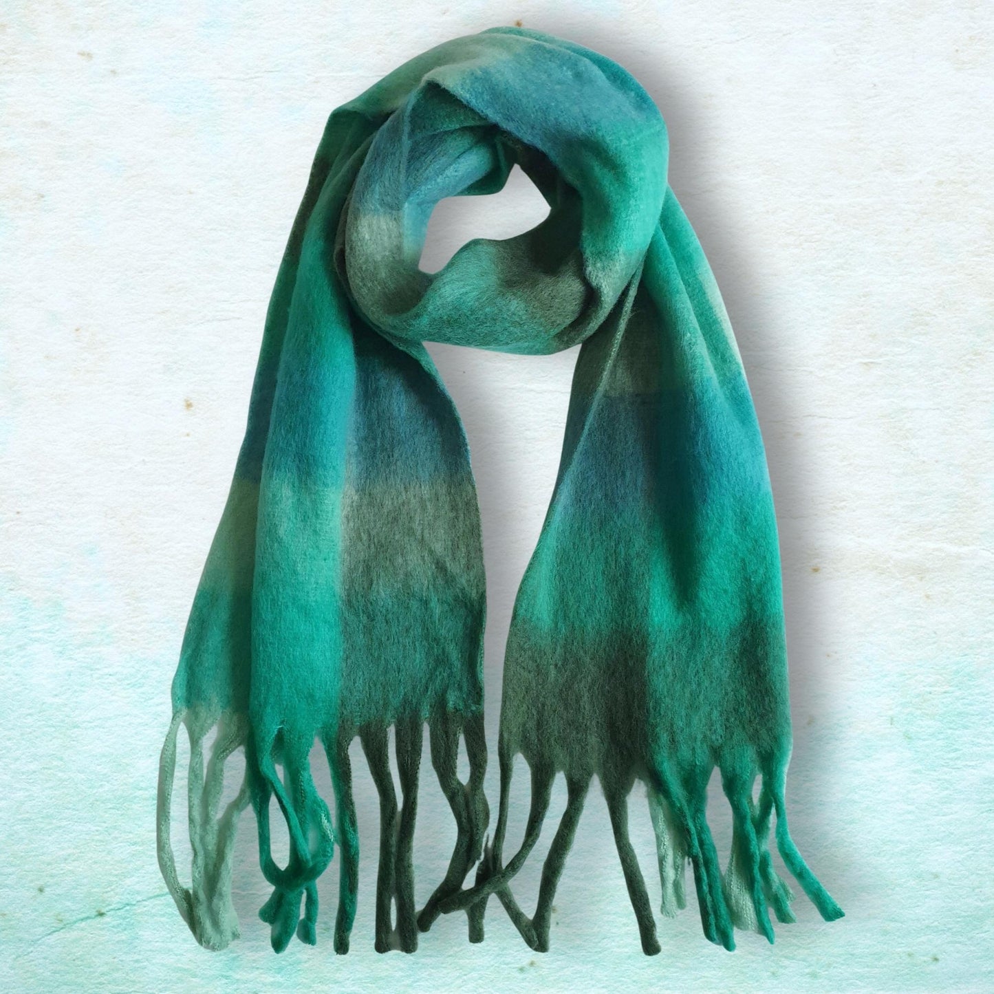 Green scarf with fringes on a light blue textured background