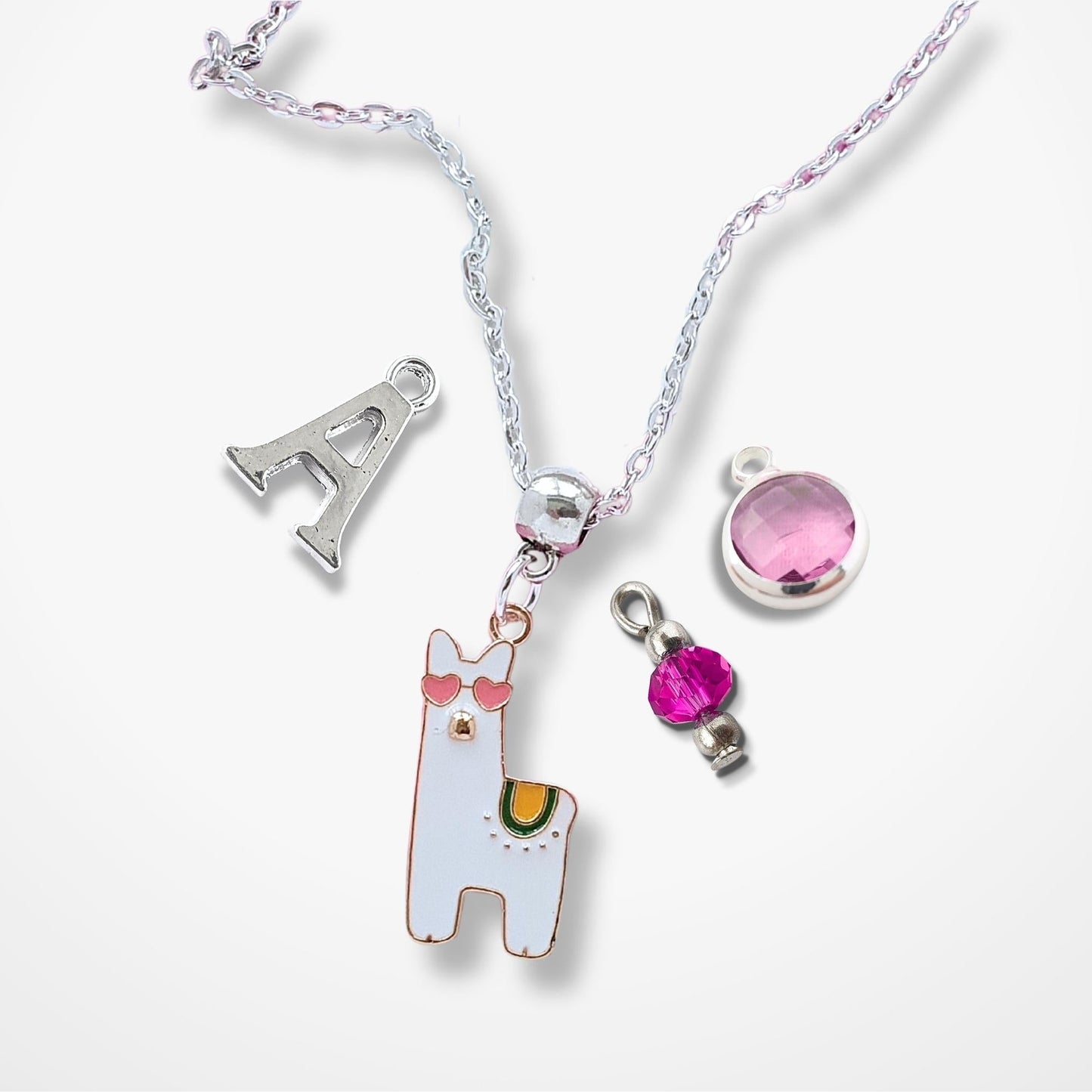 Necklace with various charms including a llama, letter 'A', and pink gem on a white background