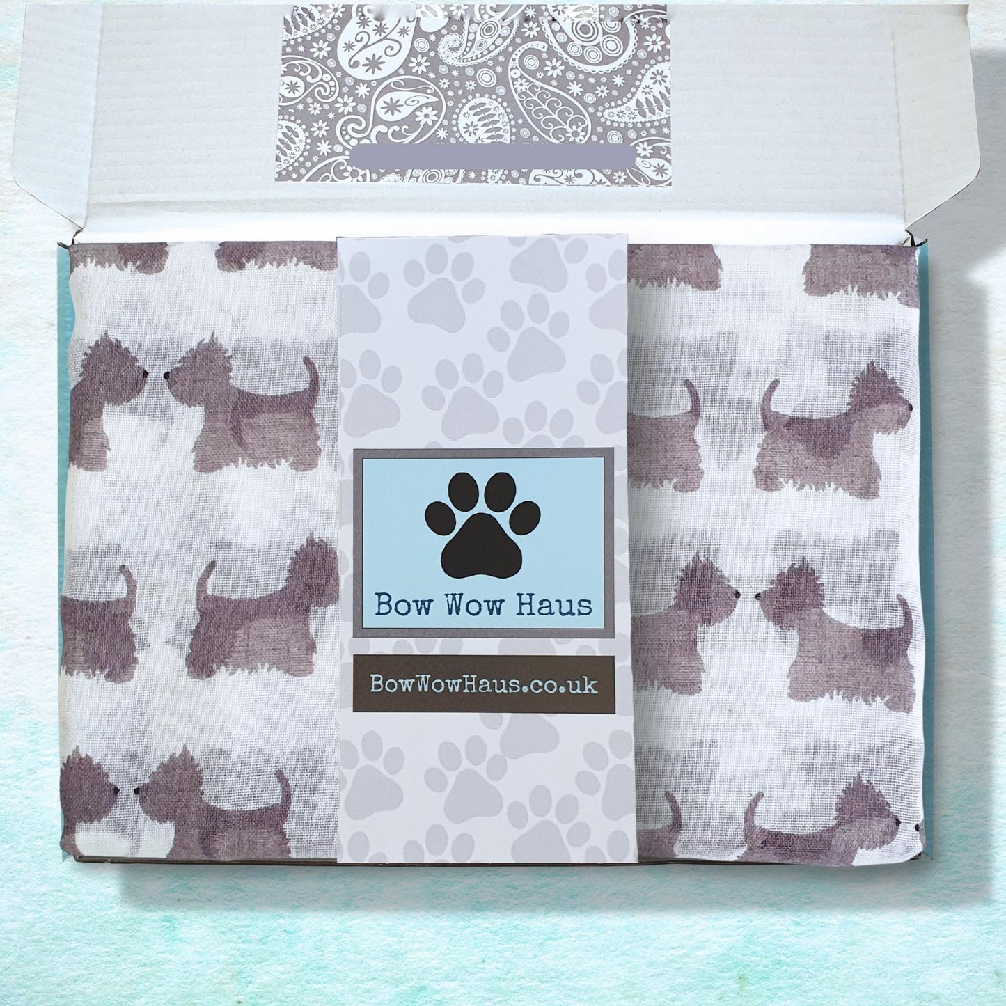Product packaging for a scotty dog scarf with 'Bow Wow Haus' branding featuring dog illustrations on a light blue background.