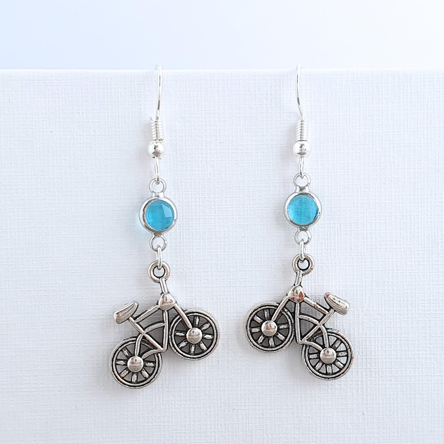 Bicycle-shaped earrings with turquoise stones on a white background