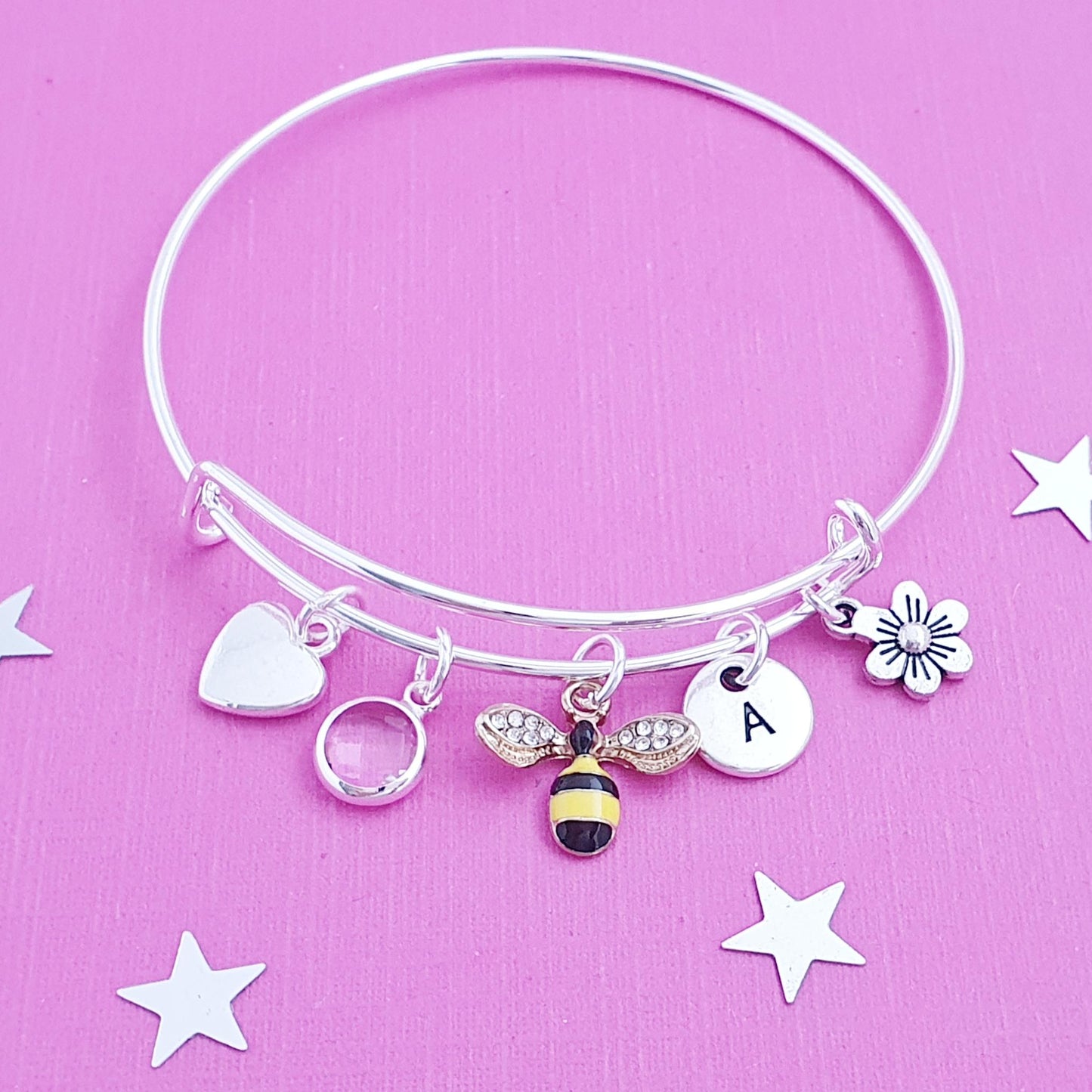 Silver bracelet with charms on a pink background