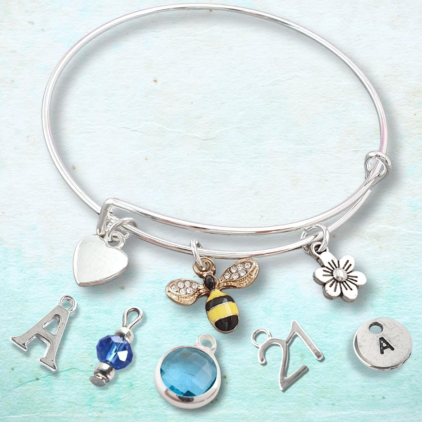 Silver adjustable bangle with various charms on a light blue background