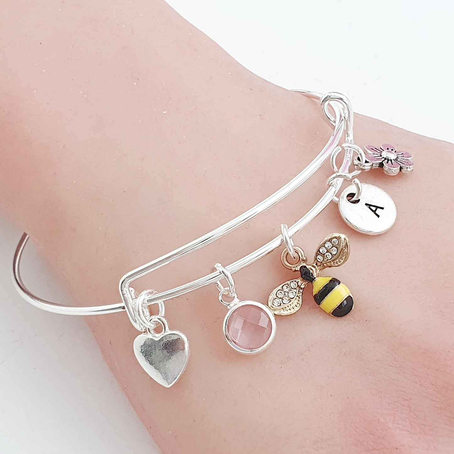 Silver bracelet with various charms on a wrist against a white background
