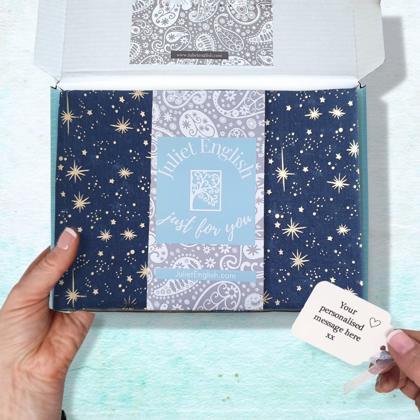Star pattern scarf folded in Juliet English box and a personalized message card on a light blue background