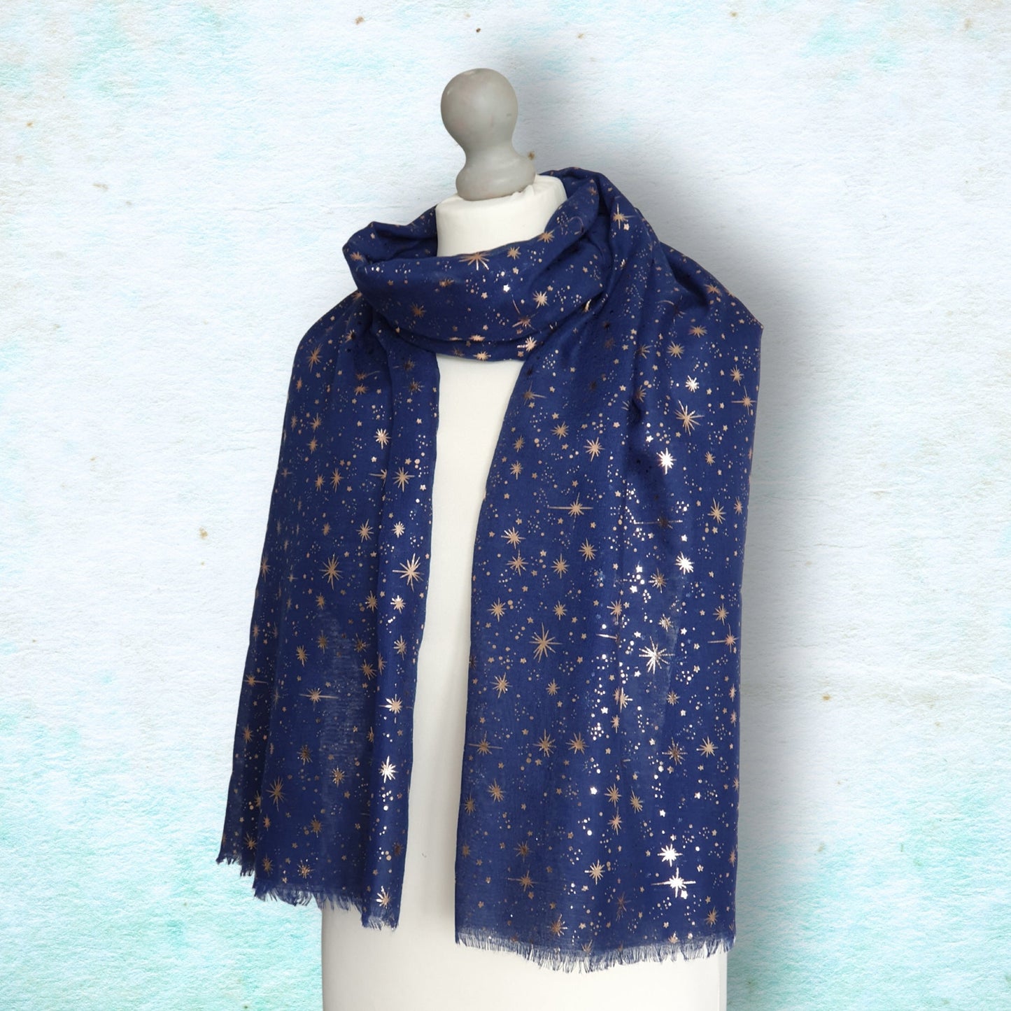 Navy blue scarf with star pattern on a mannequin against a light blue background