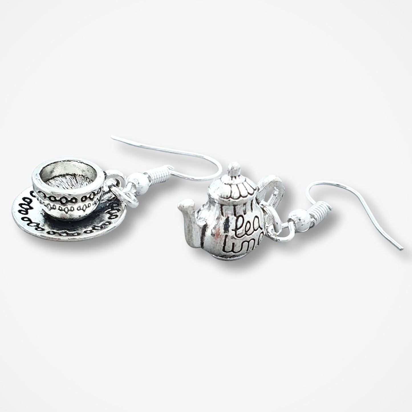 Silver teapot and teacup earrings on a white background