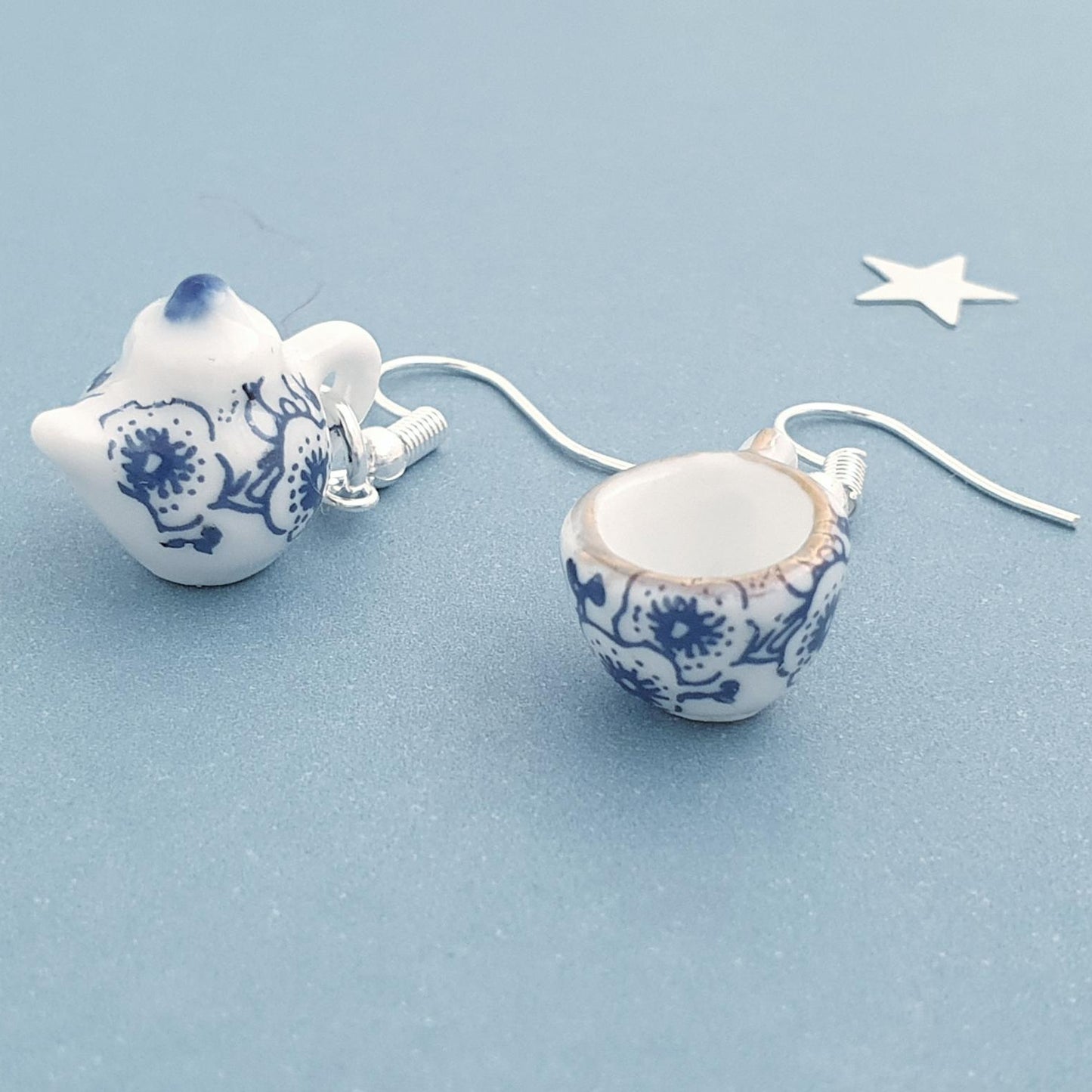 Pair of ceramic earrings with blue floral patterns on a light blue background.