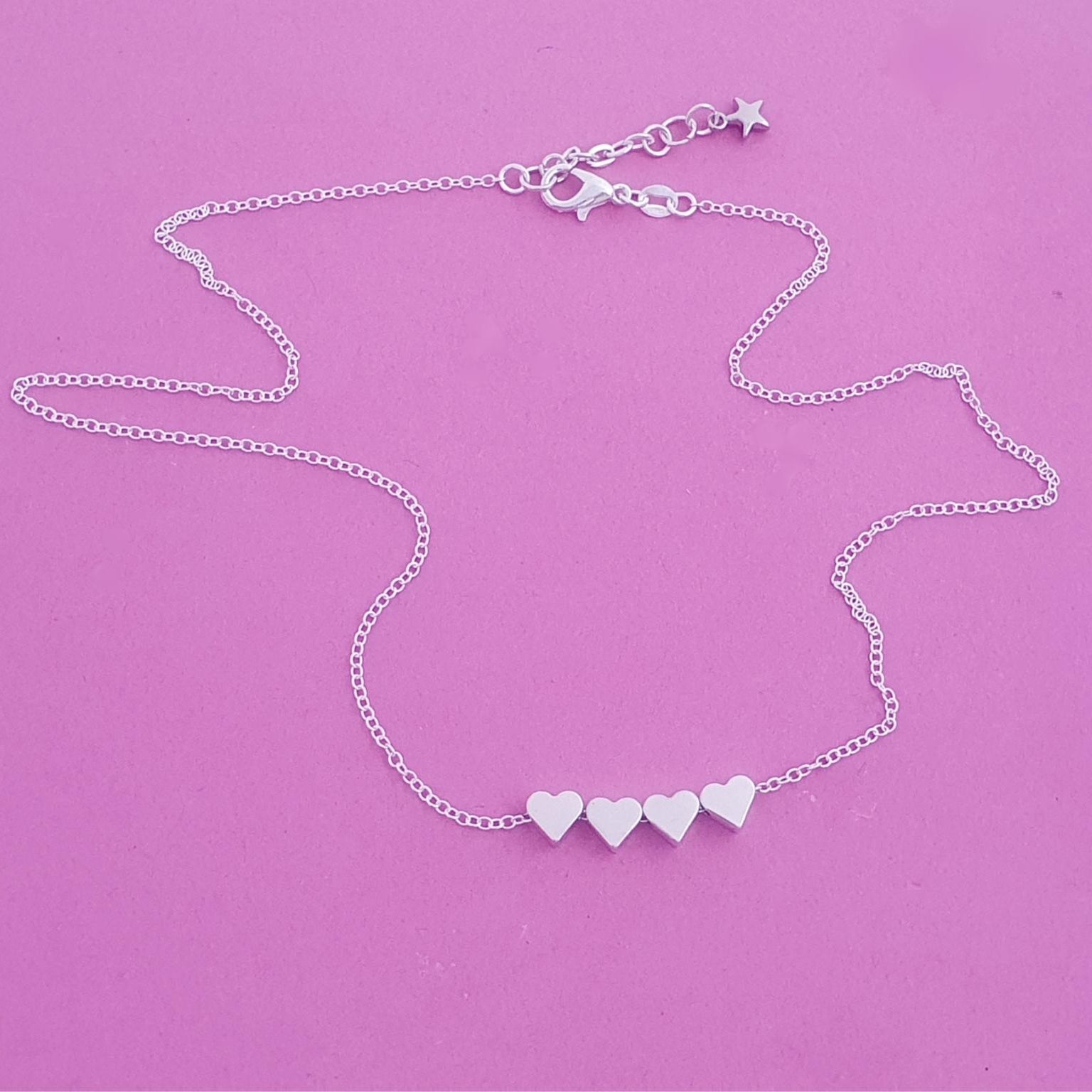 Silver necklace with heart-shaped charms on a purple background