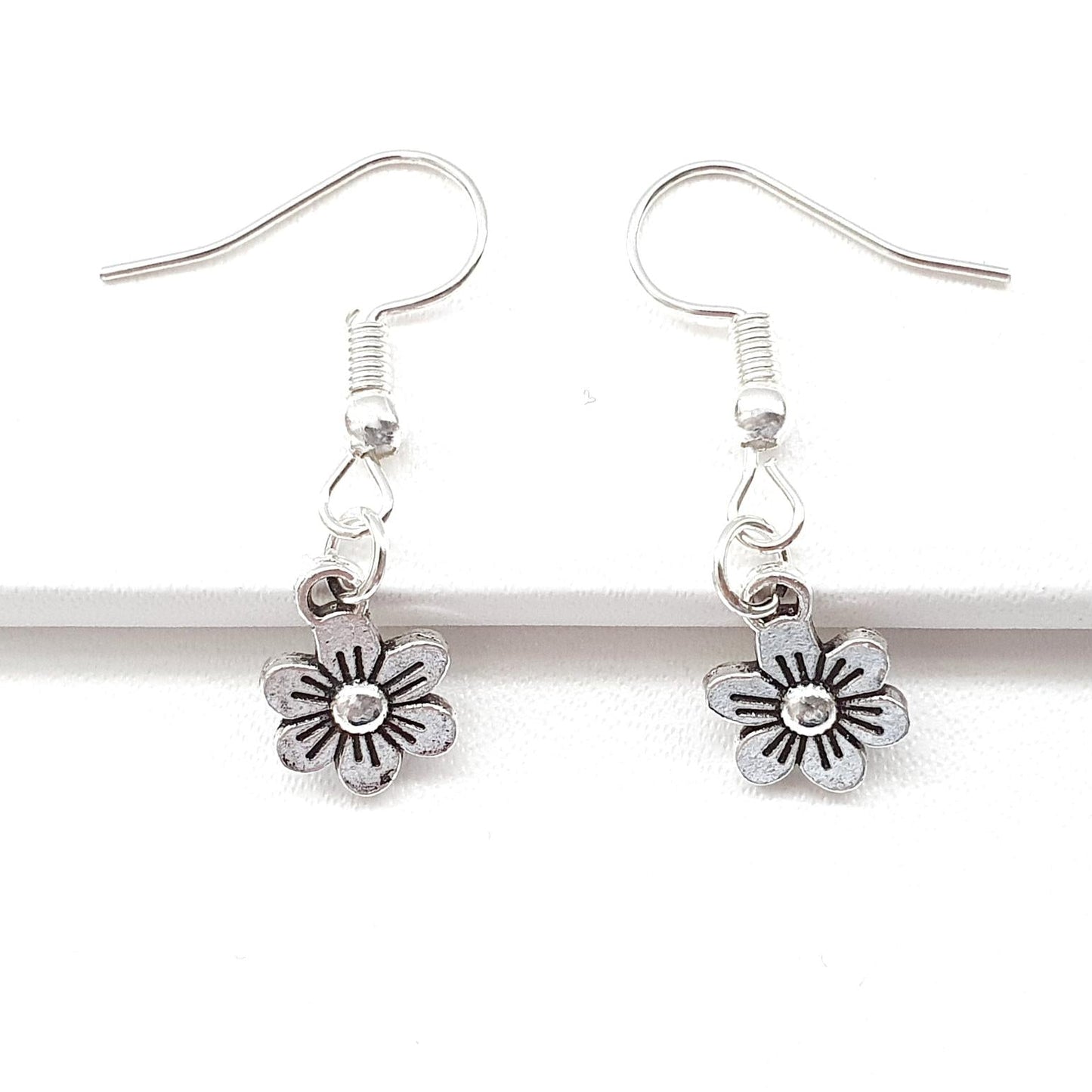 Silver flower-shaped earrings on a white background
