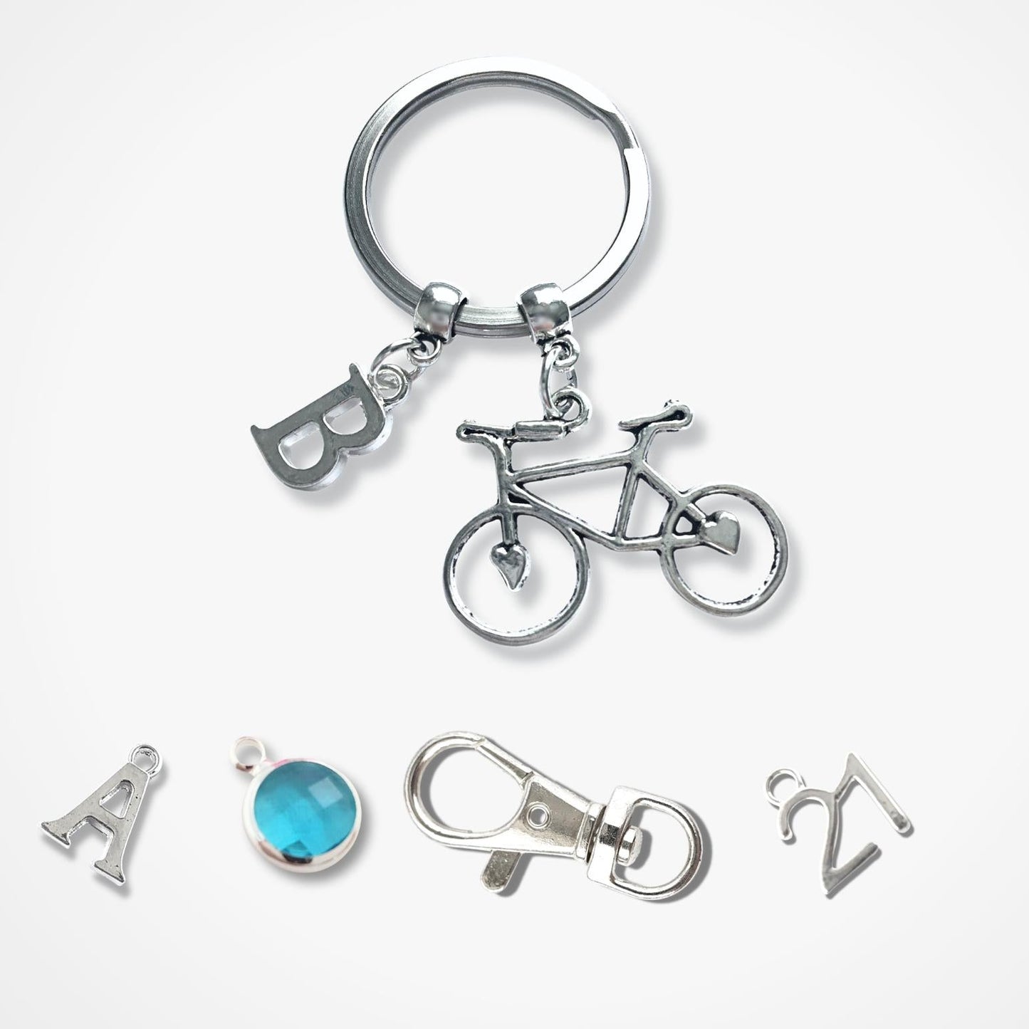 Silver keychain with bicycle charm and other small accessories on a white background