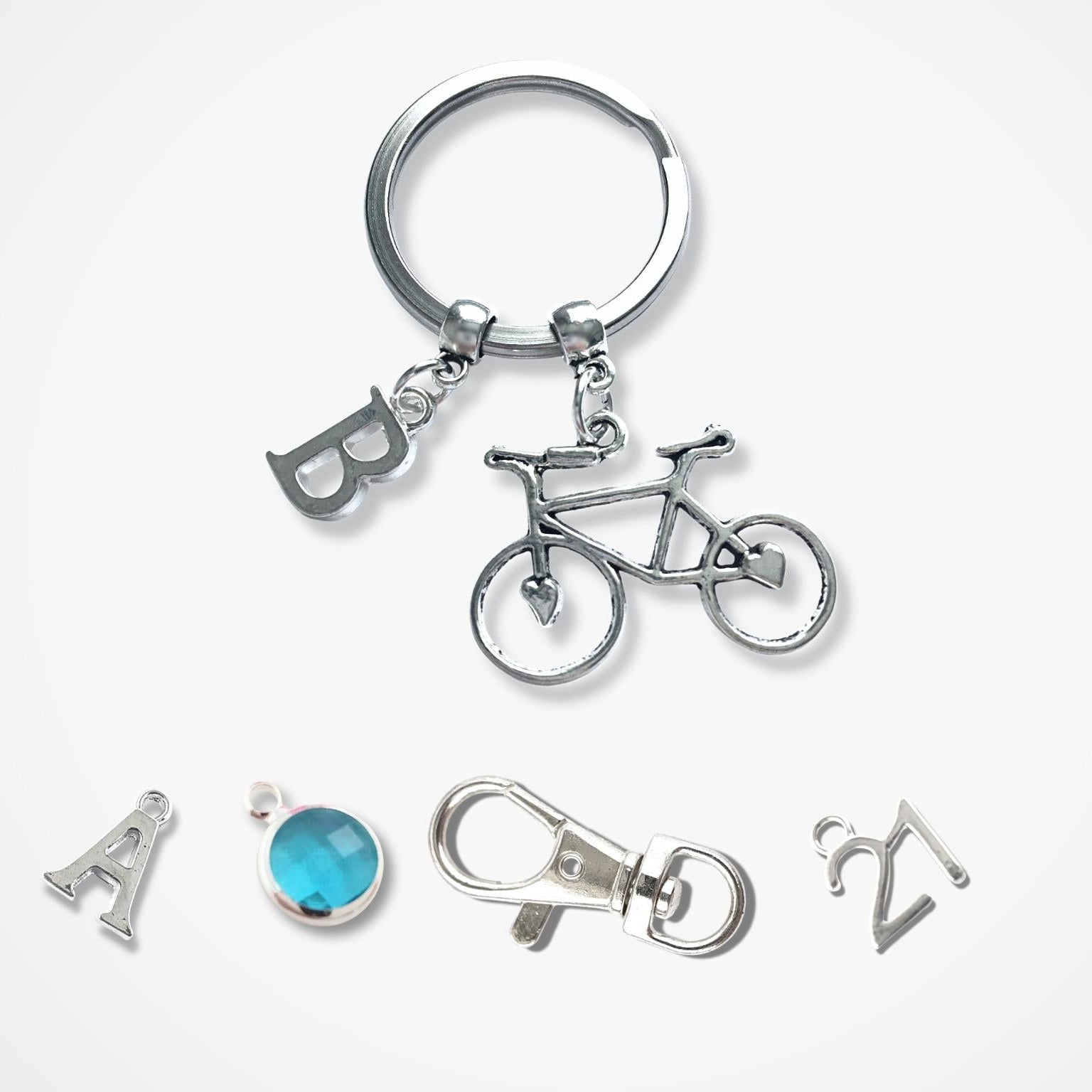 Silver keychain with bicycle charm and other small accessories on a white background