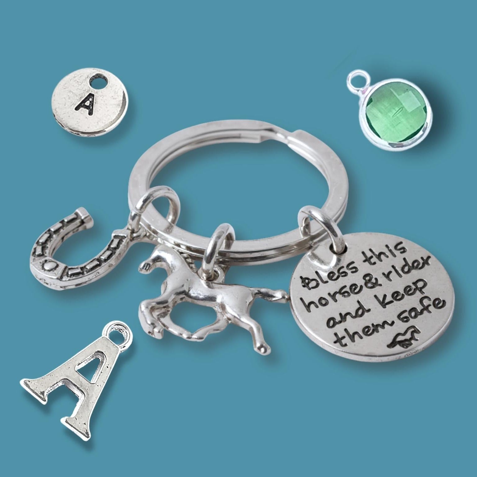 Silver keychain with horse and rider charm, letter 'A' charm, and green gemstone on a blue background