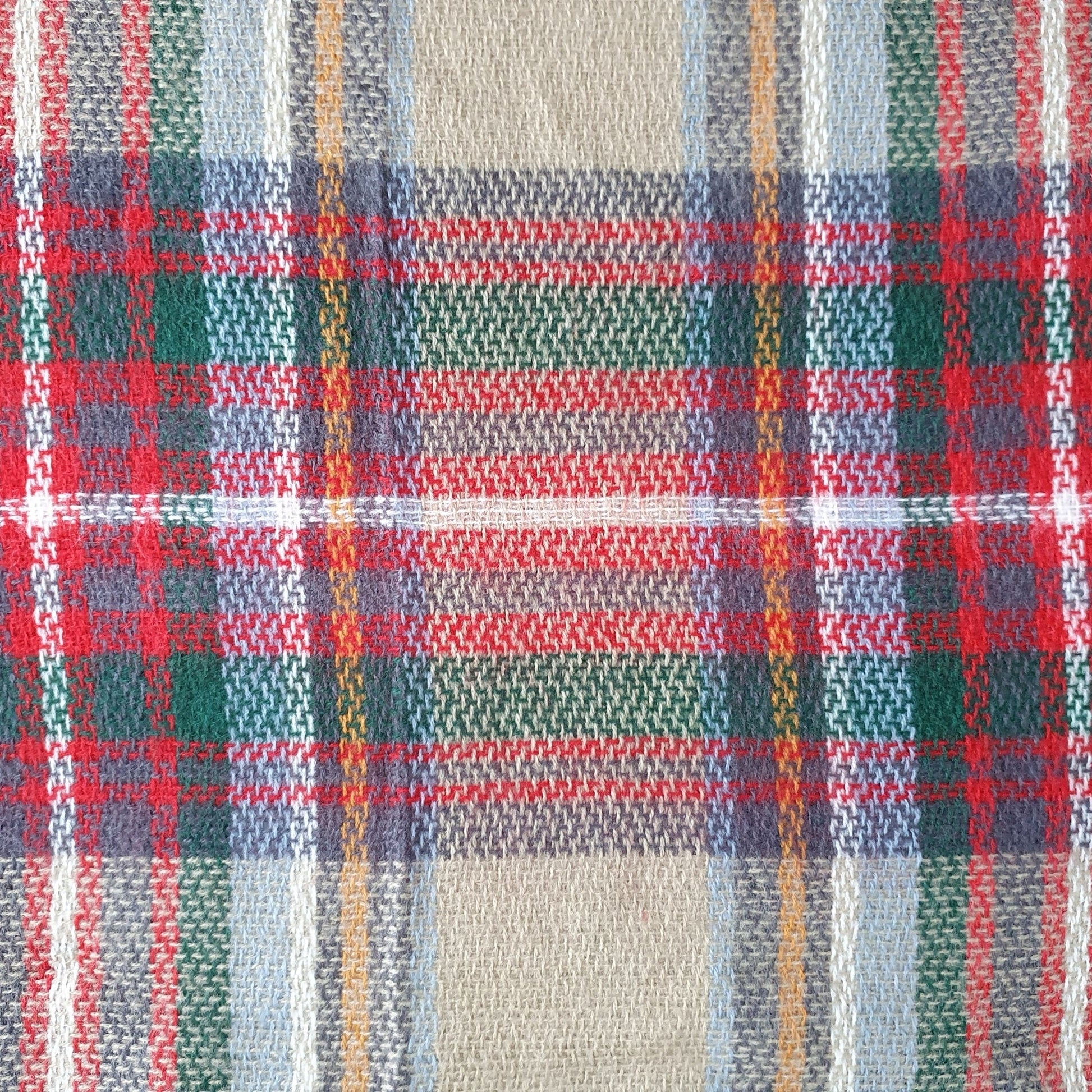 Close-up of a plaid fabric with red, blue, green, and beige colors.