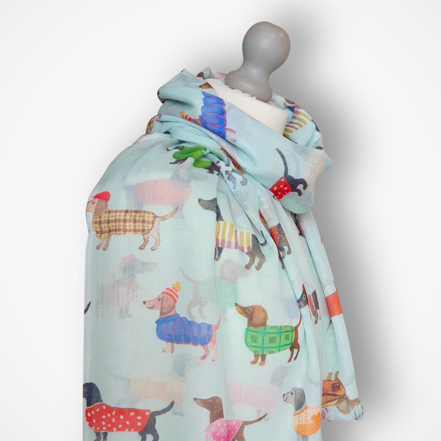 Mannequin wearing a colorful scarf with sausage dog patterns on a light gray background