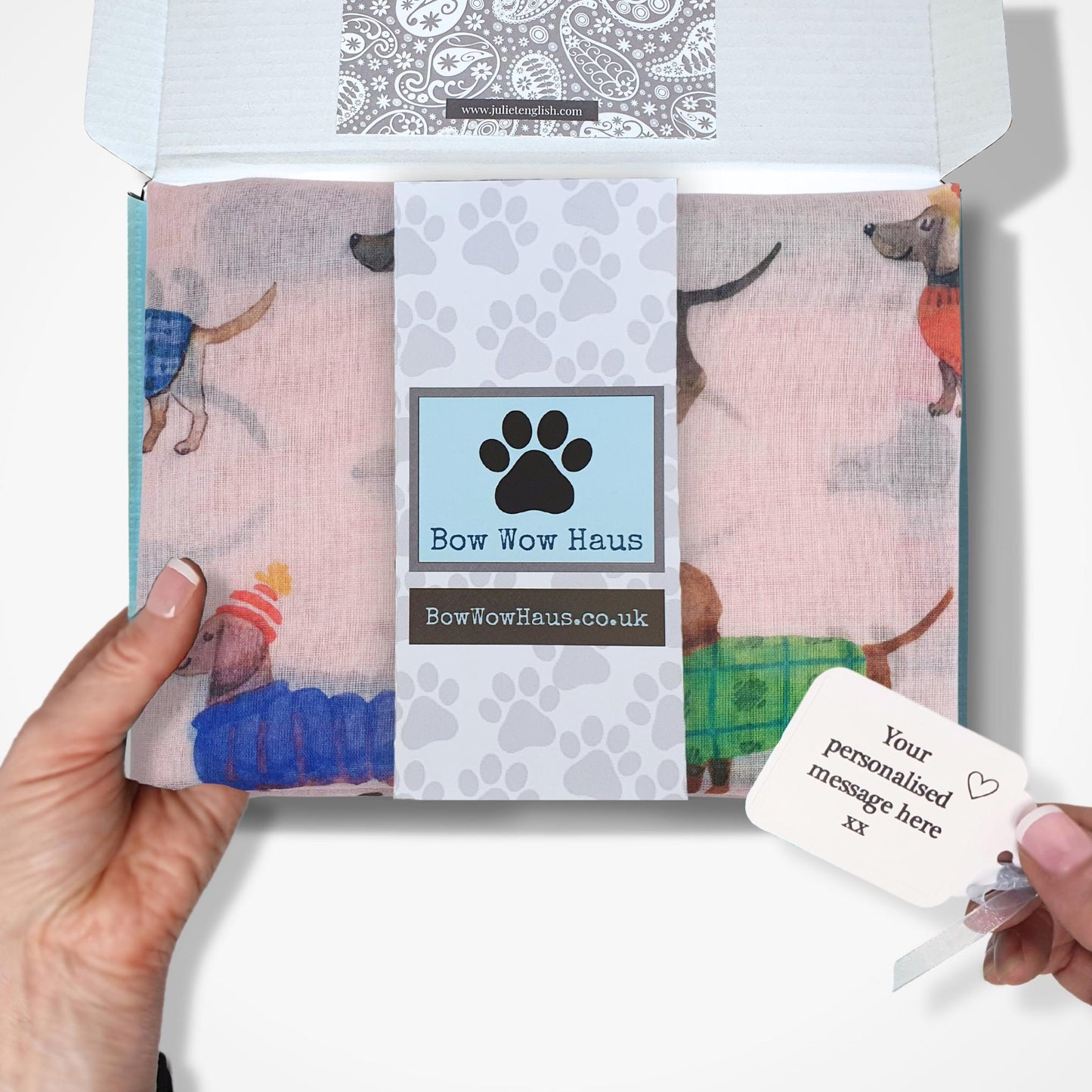 Gift boxed dachshund scarf with a personalized message card, held by a hand against a white background.