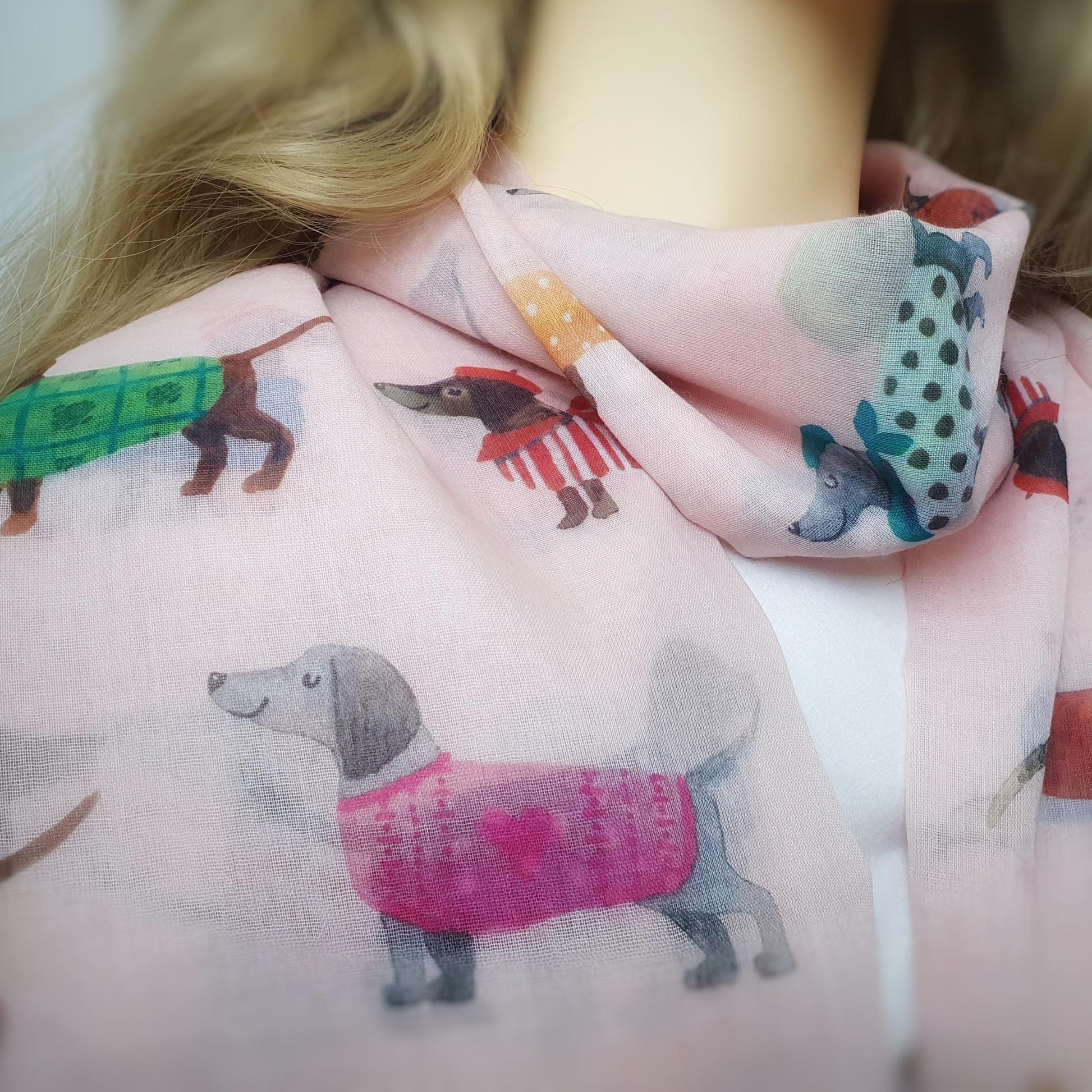 Person wearing a pink scarf with dog-themed designs.