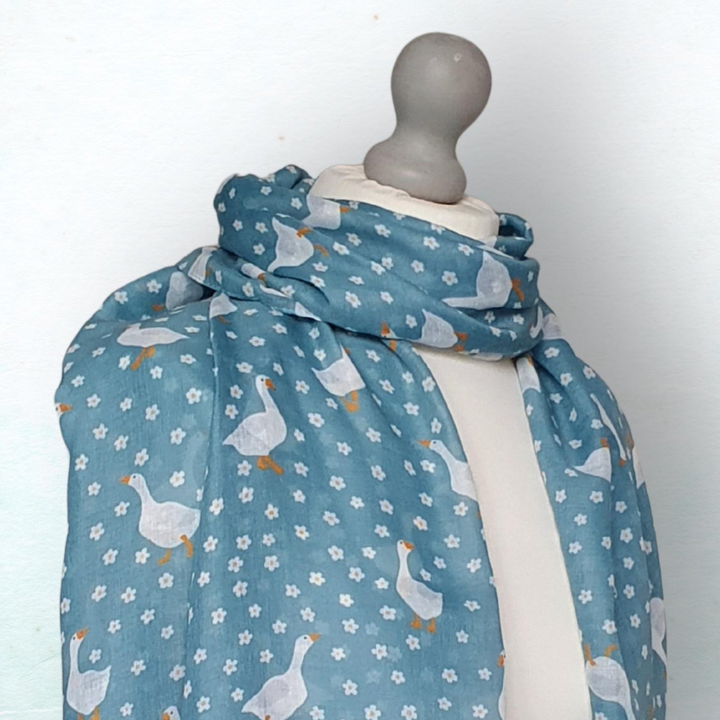 Mannequin wearing a blue scarf with duck goose pattern on a white background