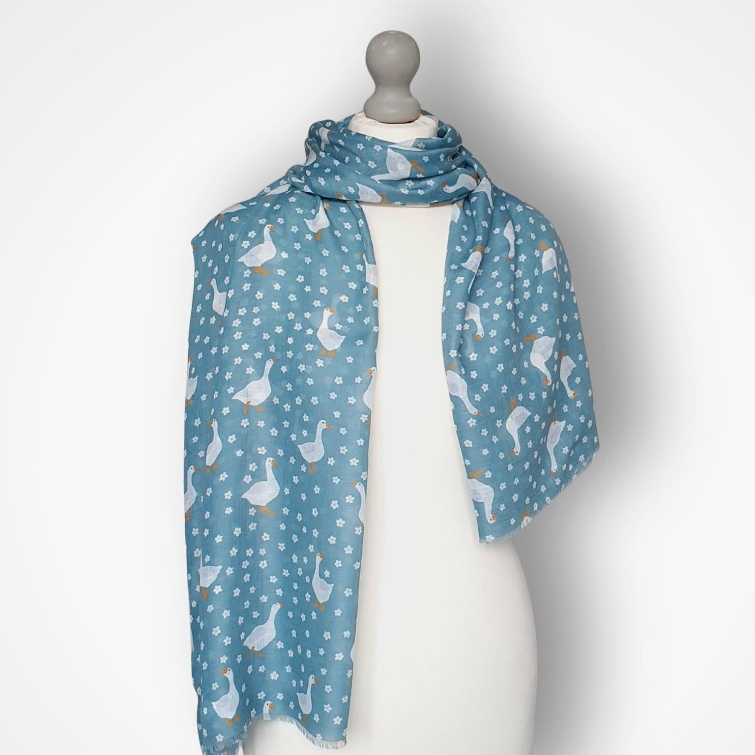 Blue goose and flower patterned scarf on a mannequin against a white background