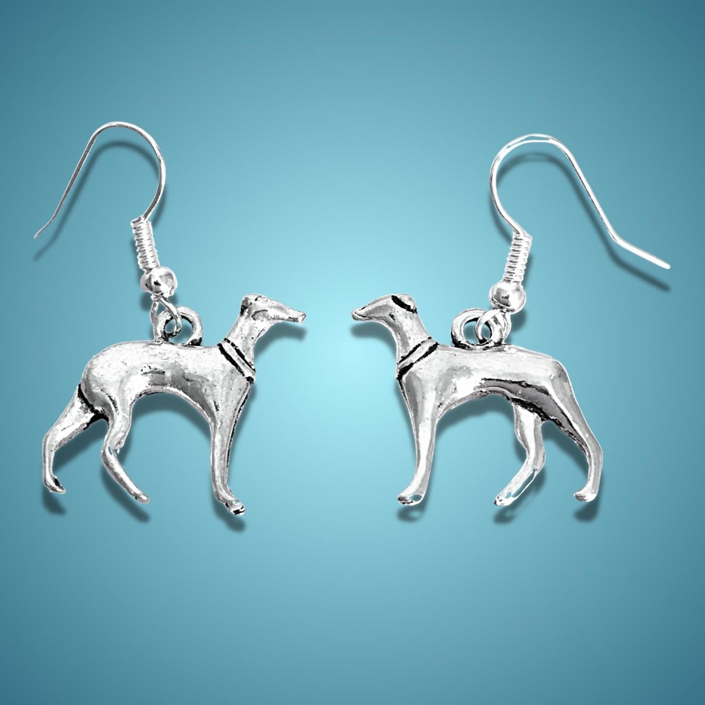 A pair of dangle earrings shaped like greyhounds, shown against a solid blue gradient background.