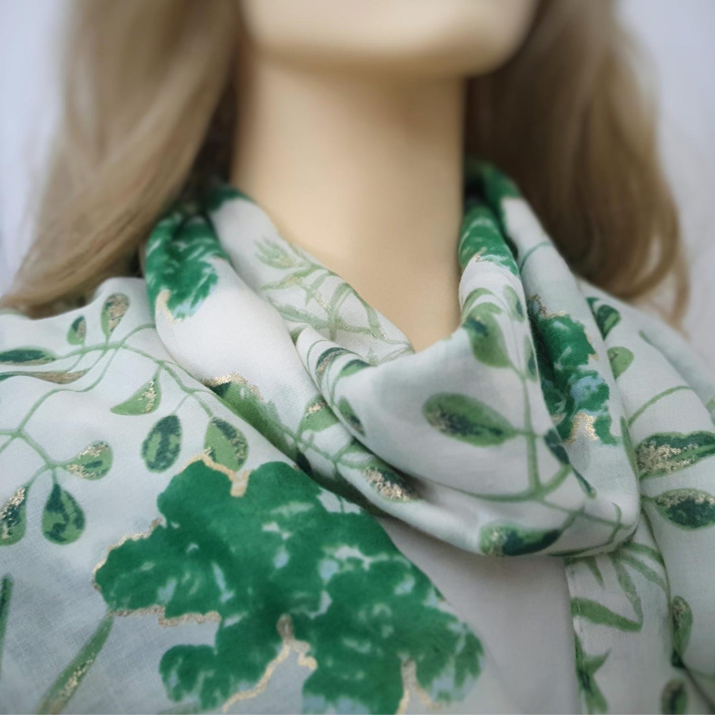 Mannequin wearing a green and white floral patterned scarf