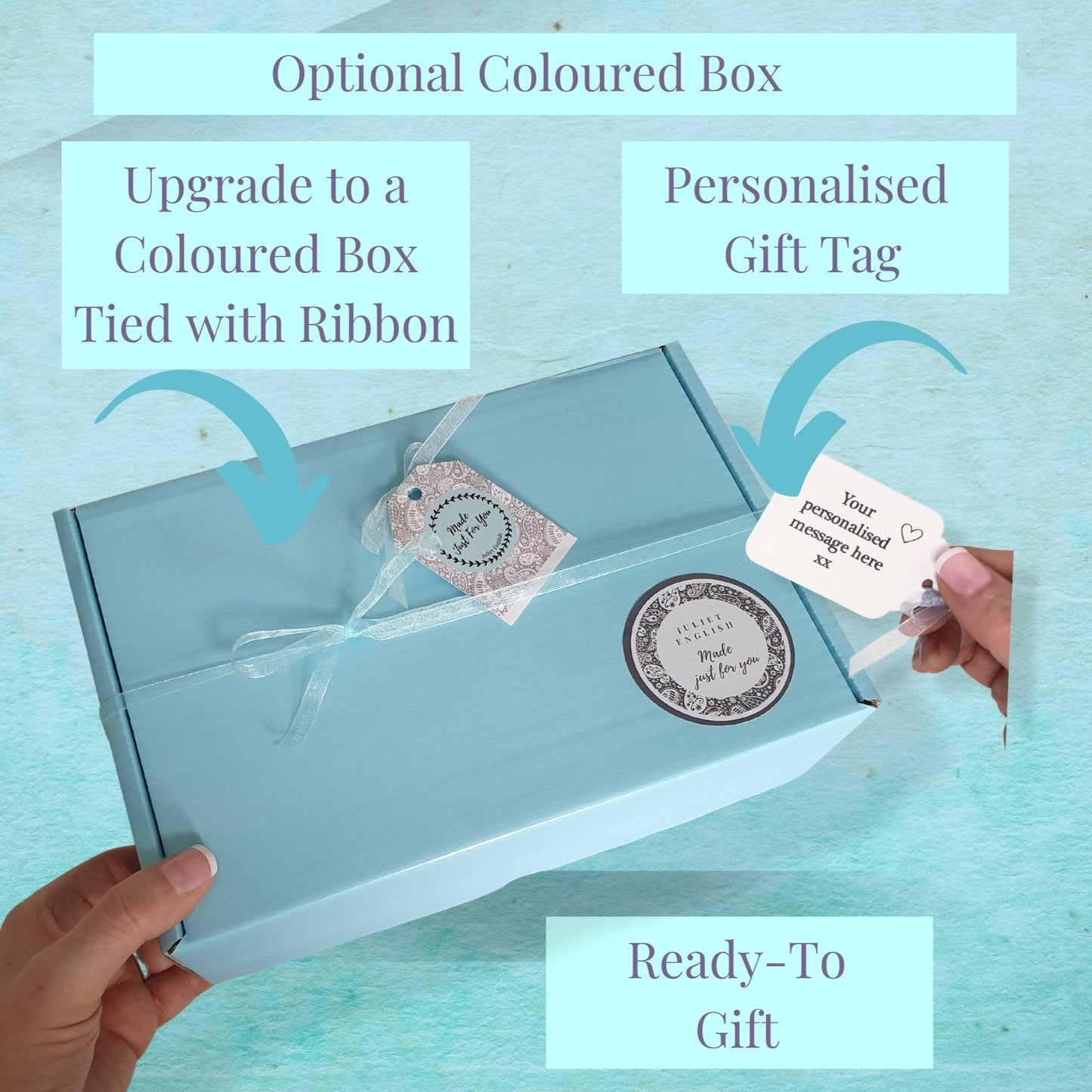 Light blue gift box with a personalised gift tag, hand holding the box against a light blue background.