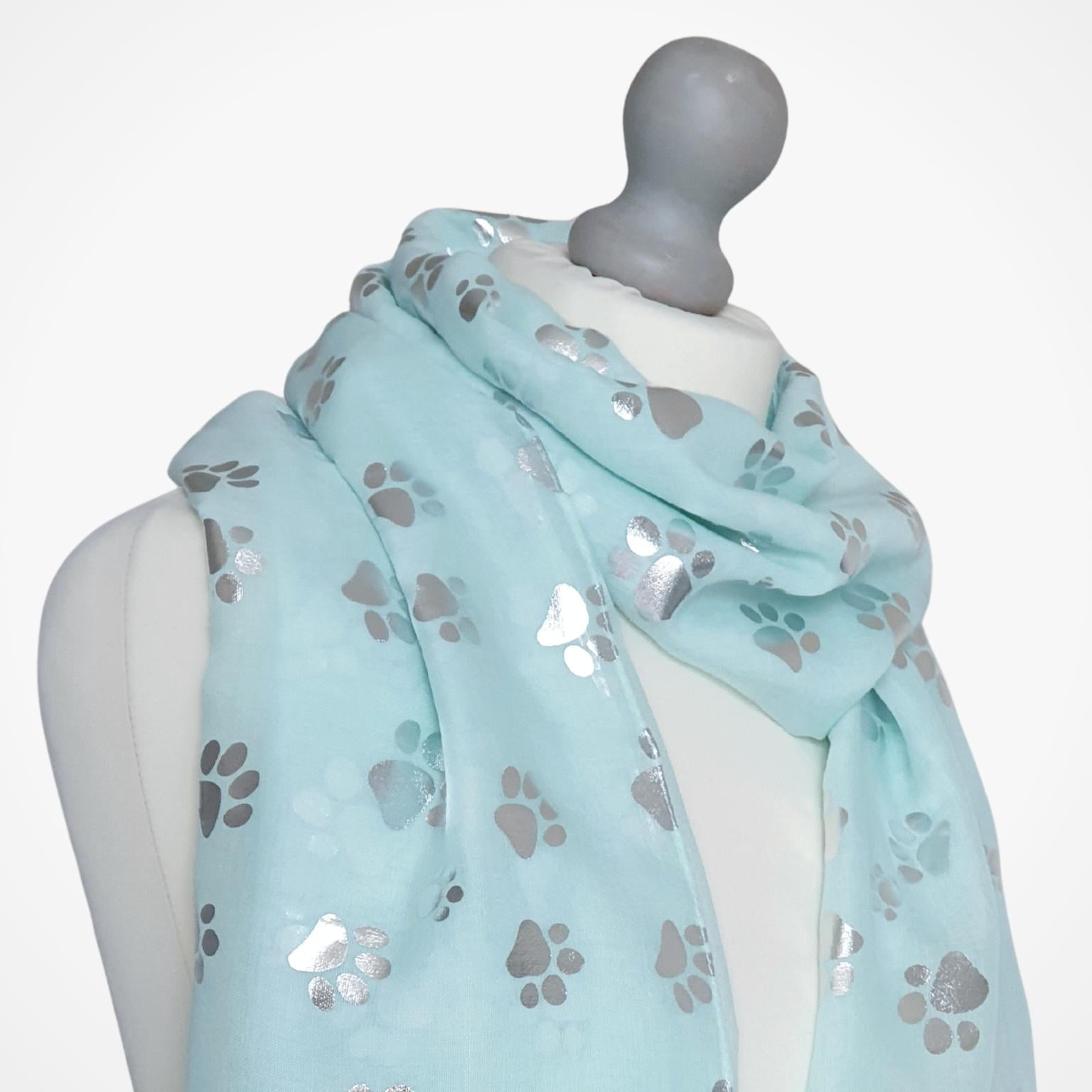 Light aqua green scarf with paw prints on a mannequin against a white background