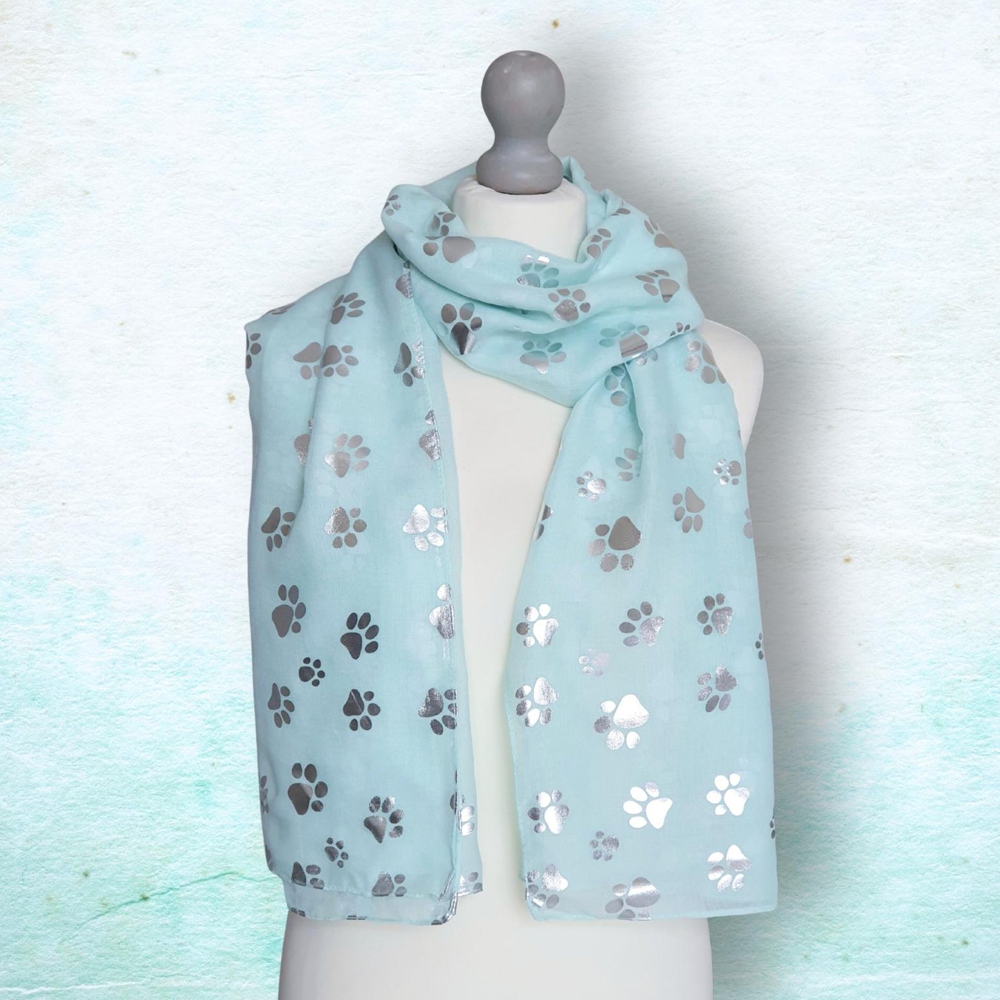 Light aqua scarf with paw print pattern on a mannequin against a light blue background