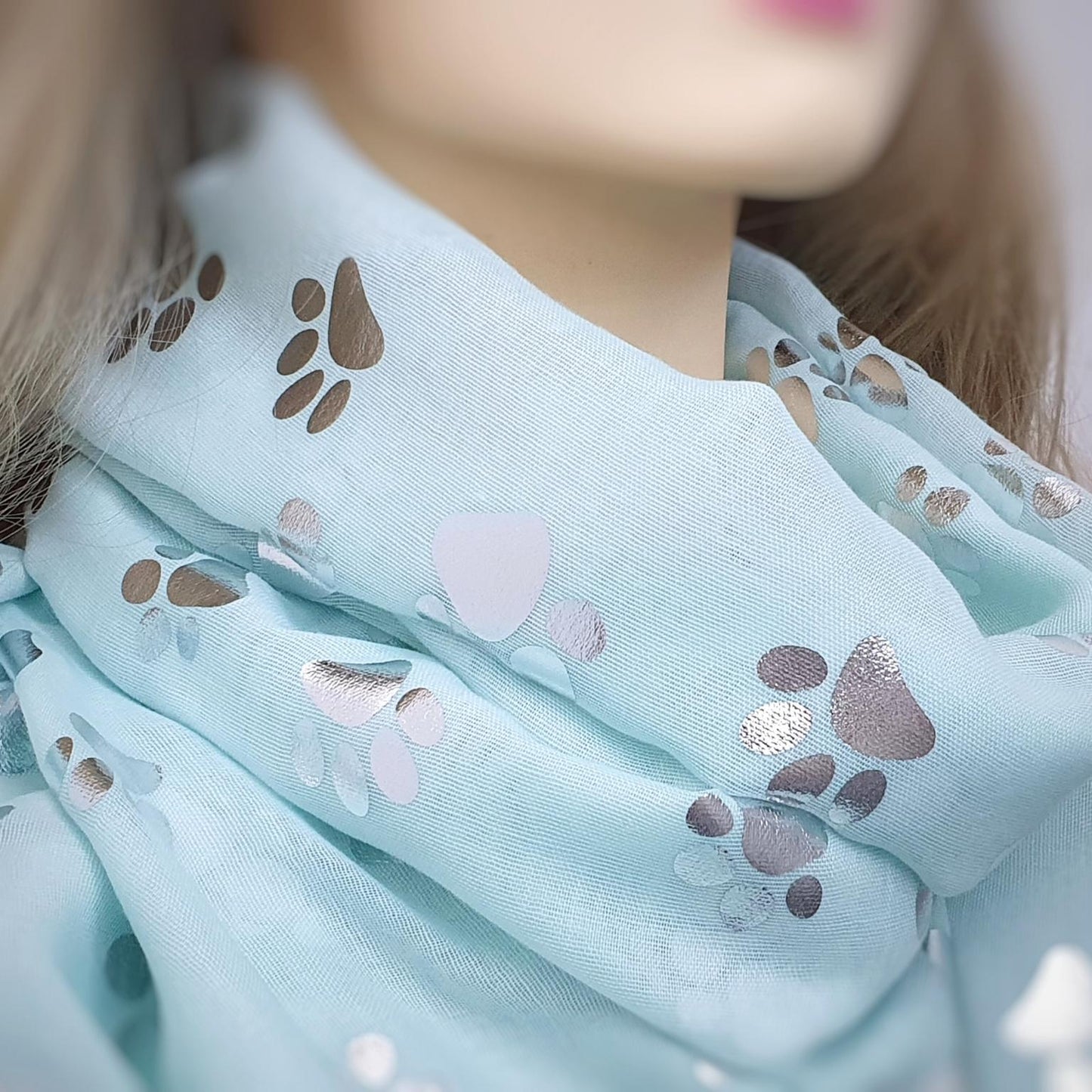Light aqua green scarf with paw print pattern worn by a mannequin