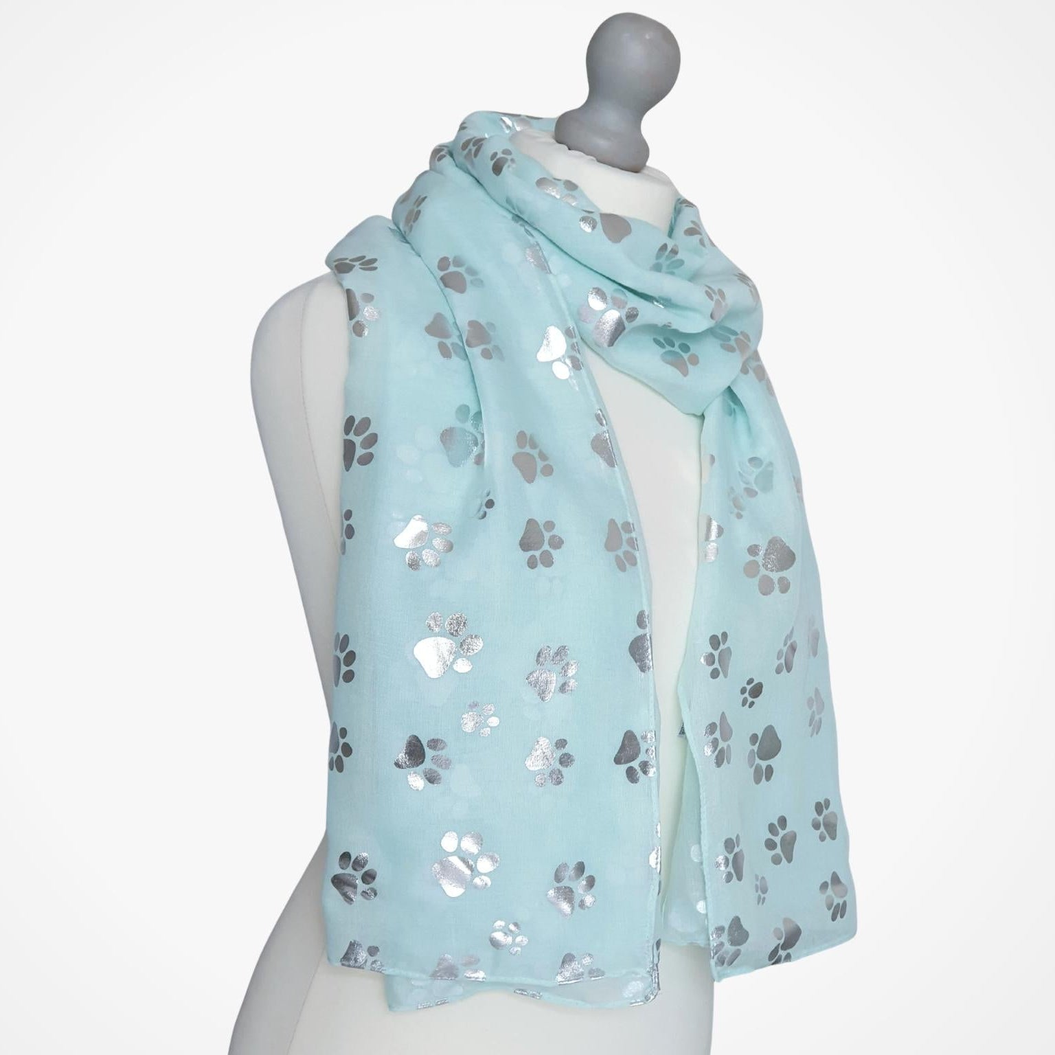 Light aqua scarf with paw print pattern on a mannequin against a white background