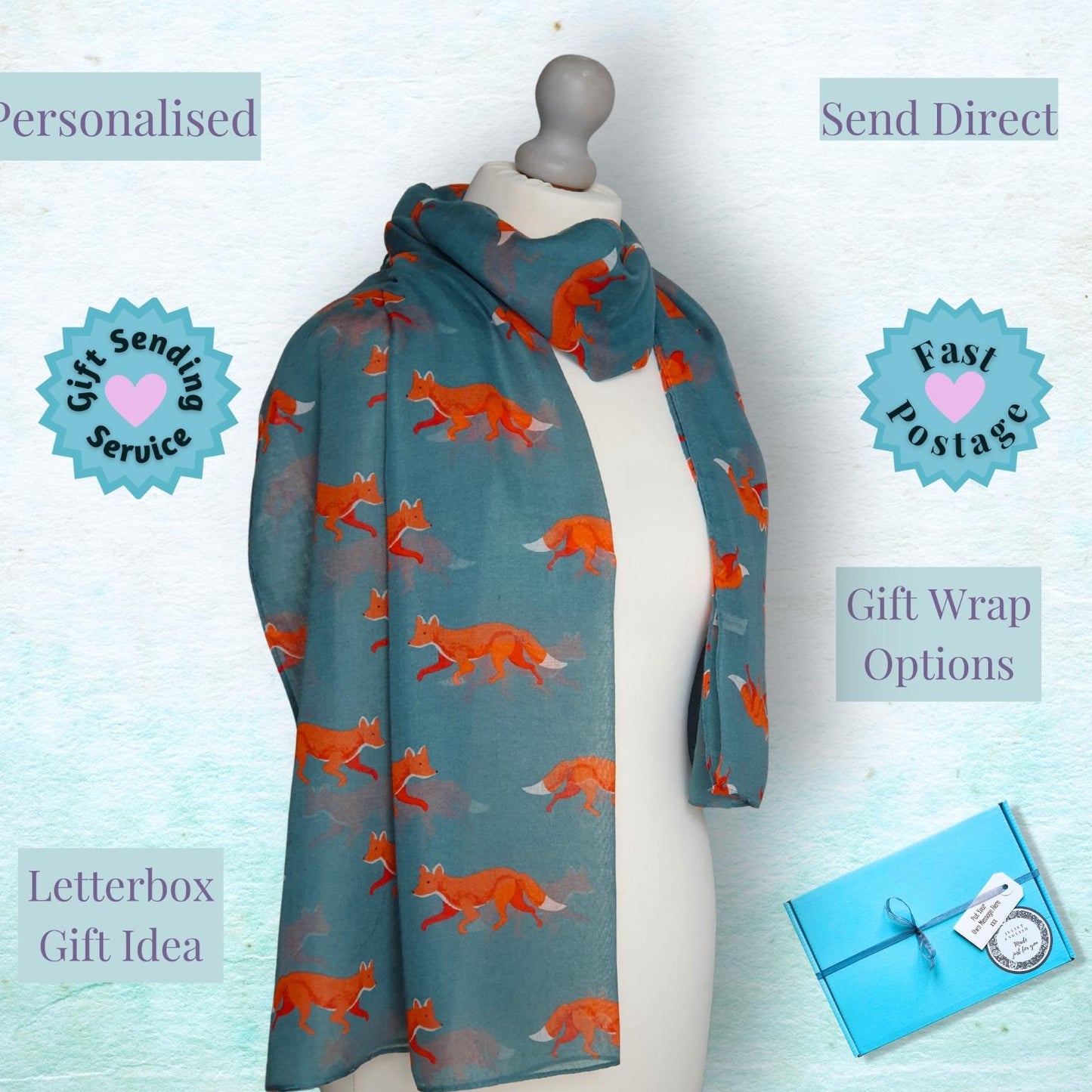 A teal scarf with an orange fox pattern draped on a white mannequin torso, surrounded by promotional text overlays and a small wrapped gift box on a light blue textured background.