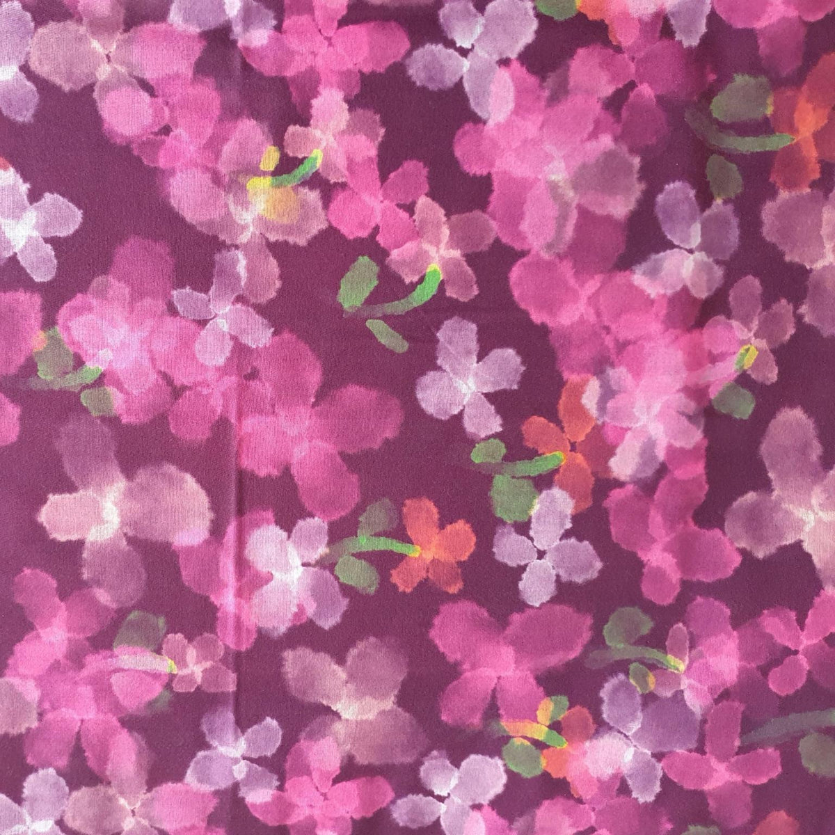 A close-up of a floral fabric pattern featuring pink and magenta blossoms with green leaves on a dark purple background.