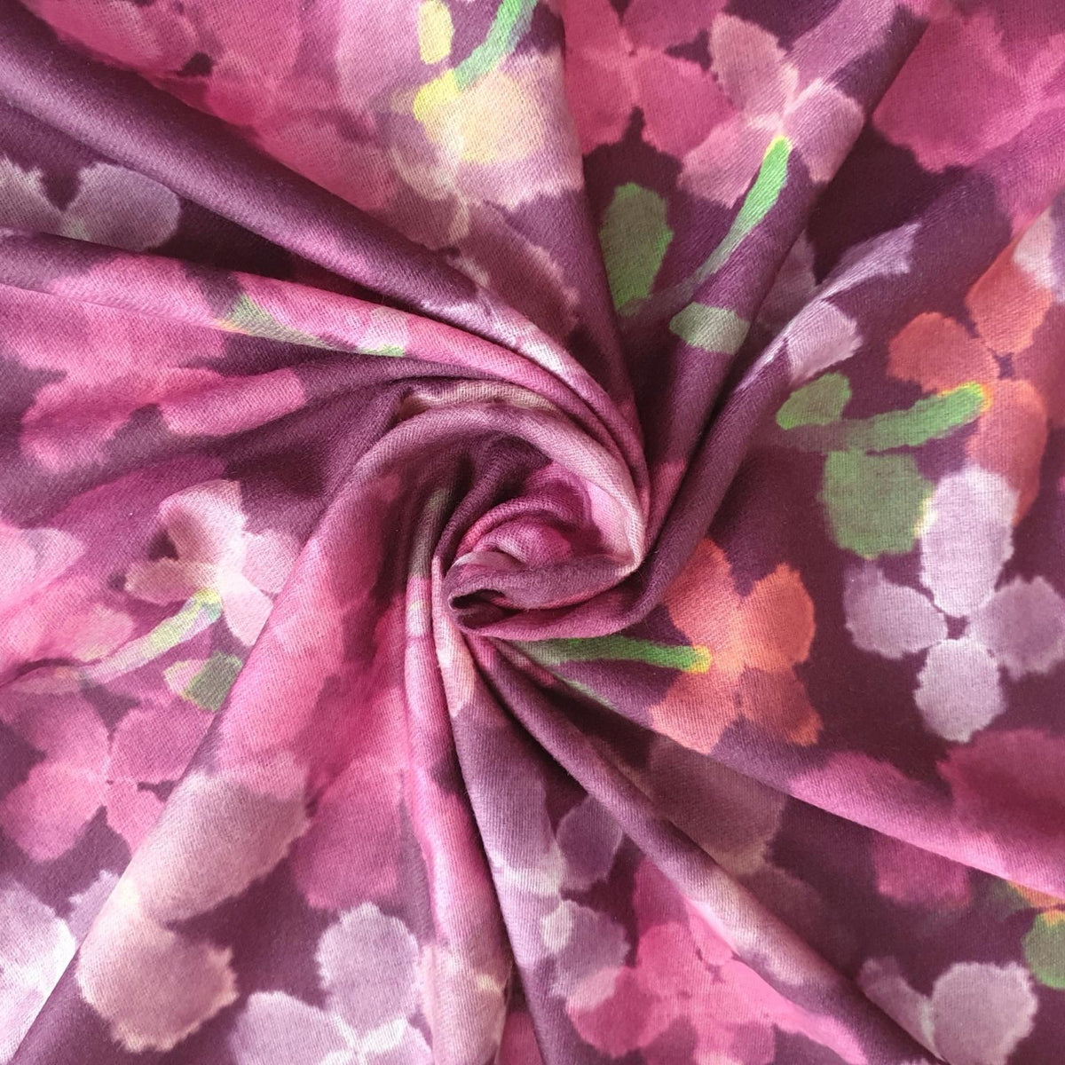 A close-up of a draped fabric with a pink and purple watercolor floral pattern, styled in a spiral twist.