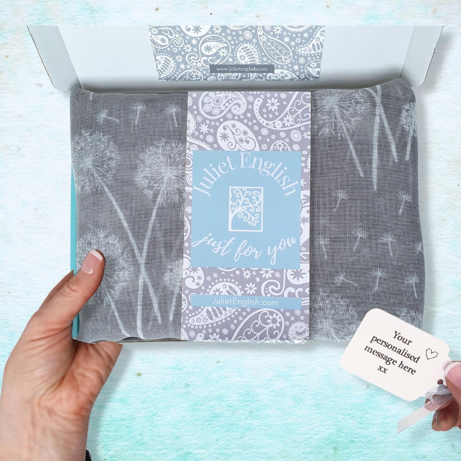 Packaged scarf with a personalized message card on a light blue background