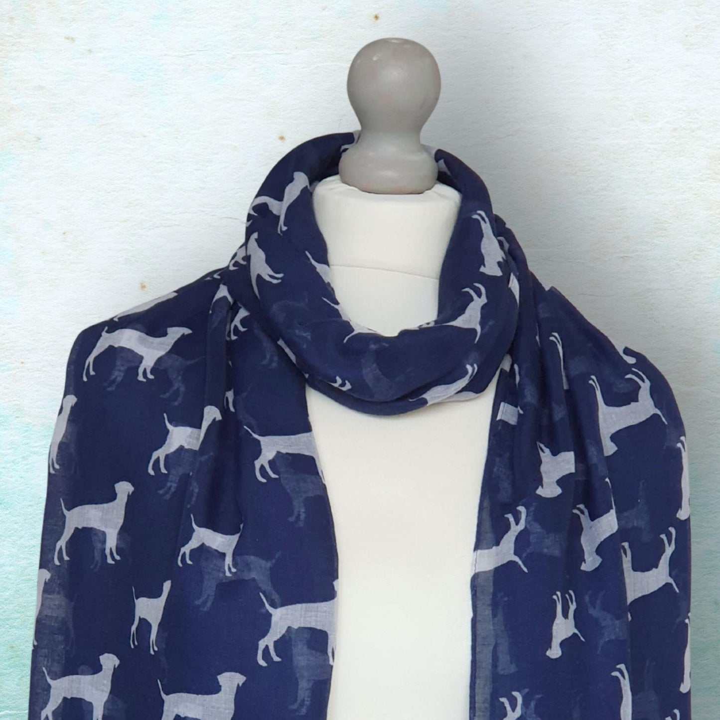 Navy blue scarf with white dog pattern on a mannequin against a light background