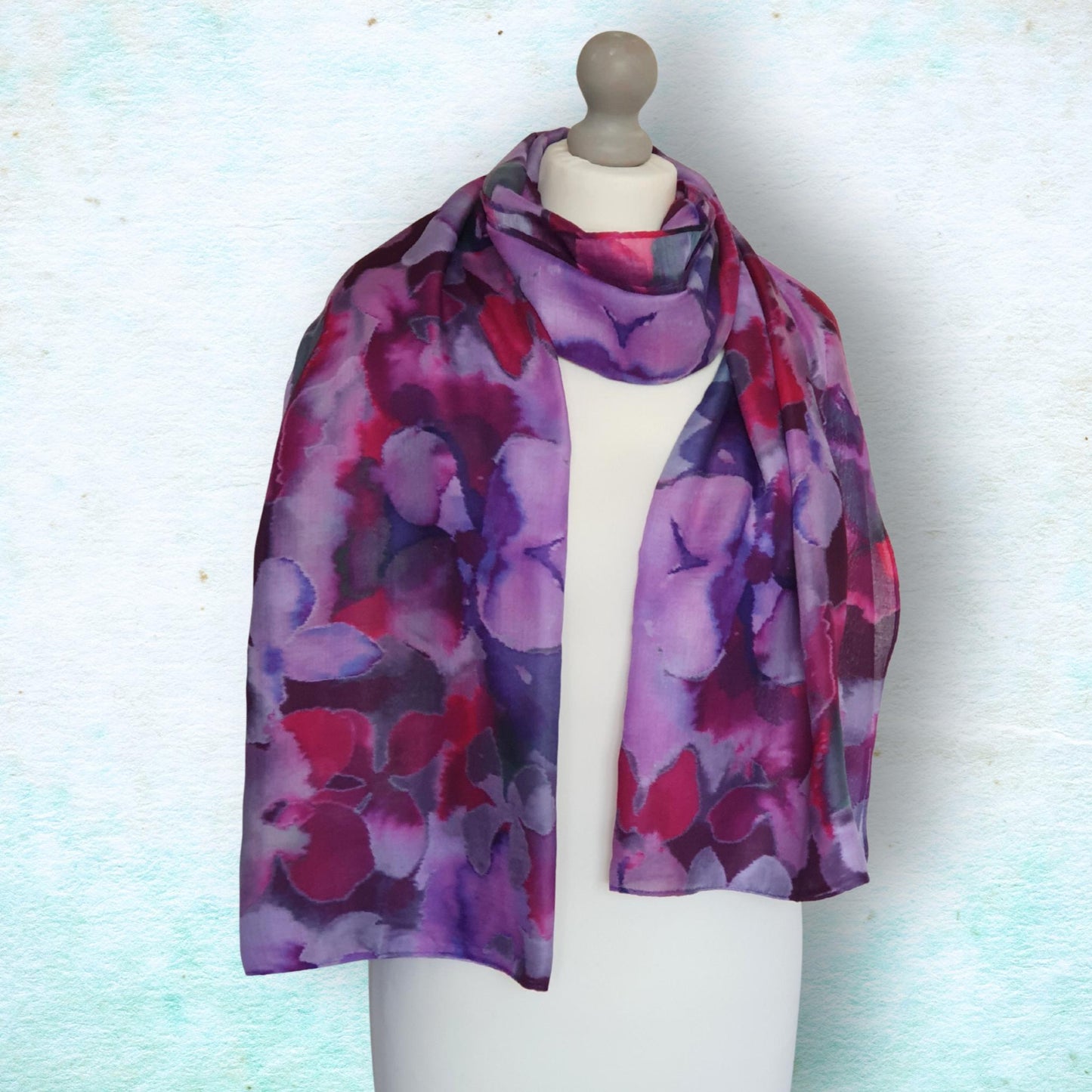 Mannequin wearing a colorful floral-patterned scarf on a light blue background