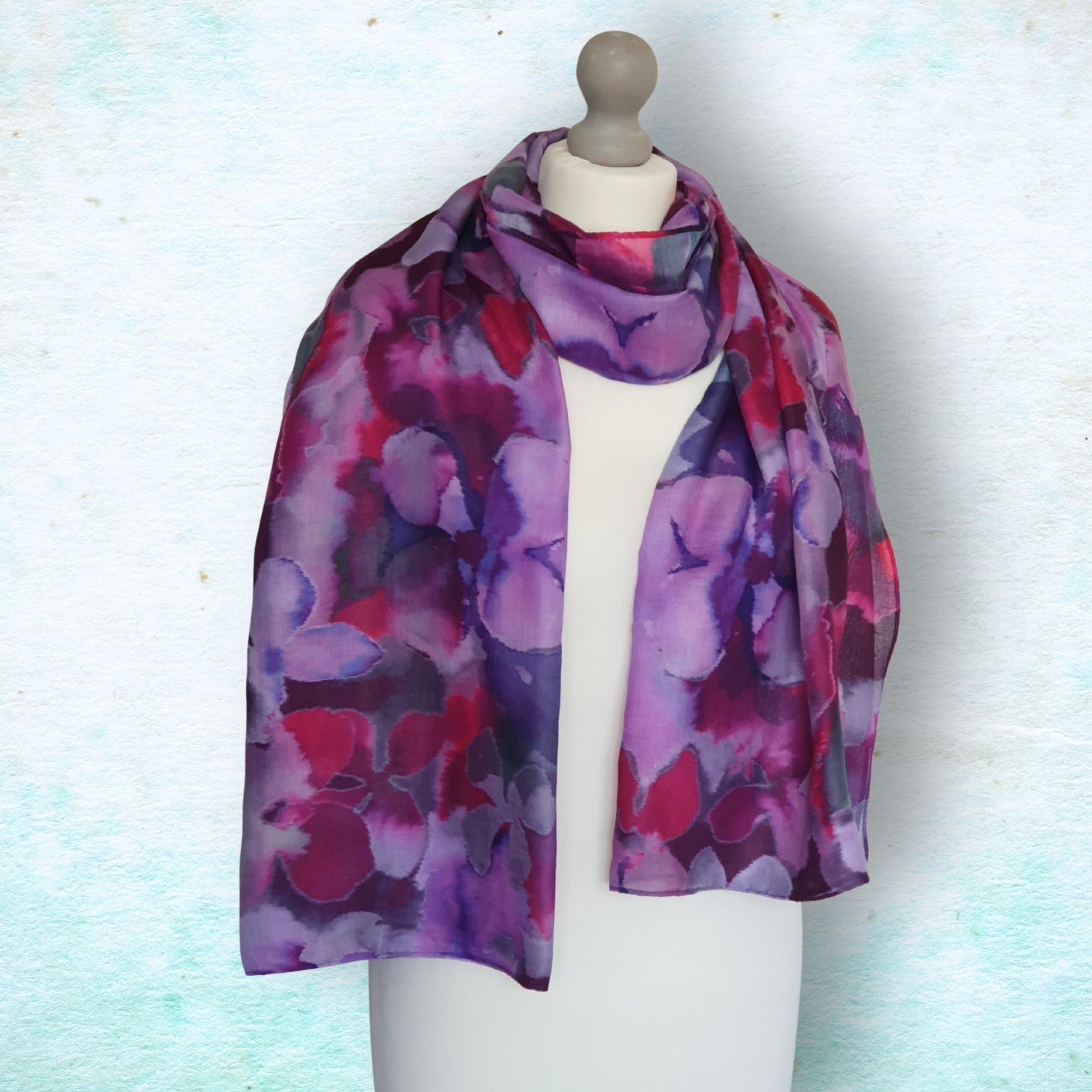 Mannequin wearing a colorful floral-patterned scarf on a light blue background