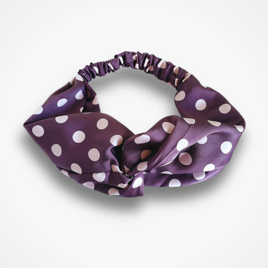 A purple satin hairband with white polka dots, displayed on a clean white background.