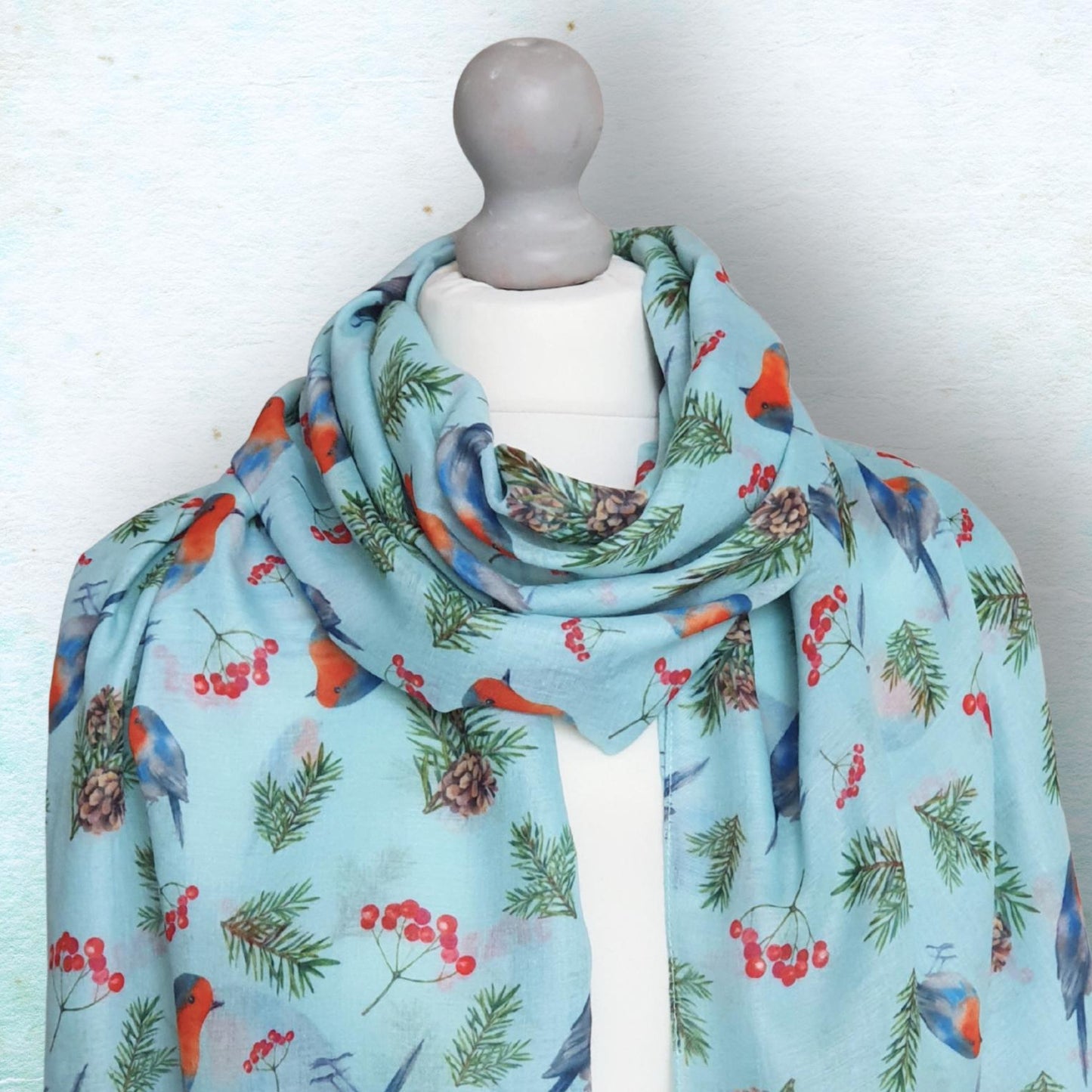 Light blue scarf with bird and berry pattern on a mannequin against a white background