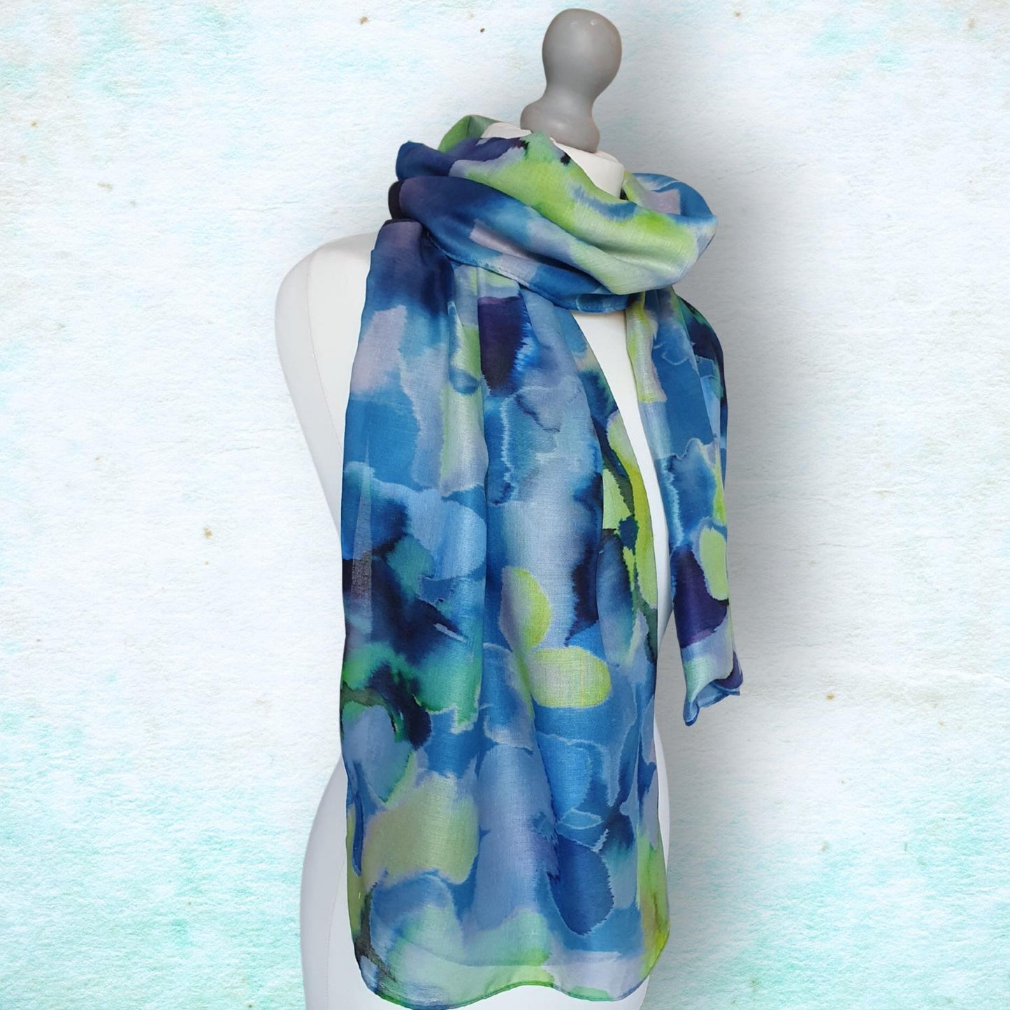 Mannequin wearing a blue and green patterned scarf against a light background