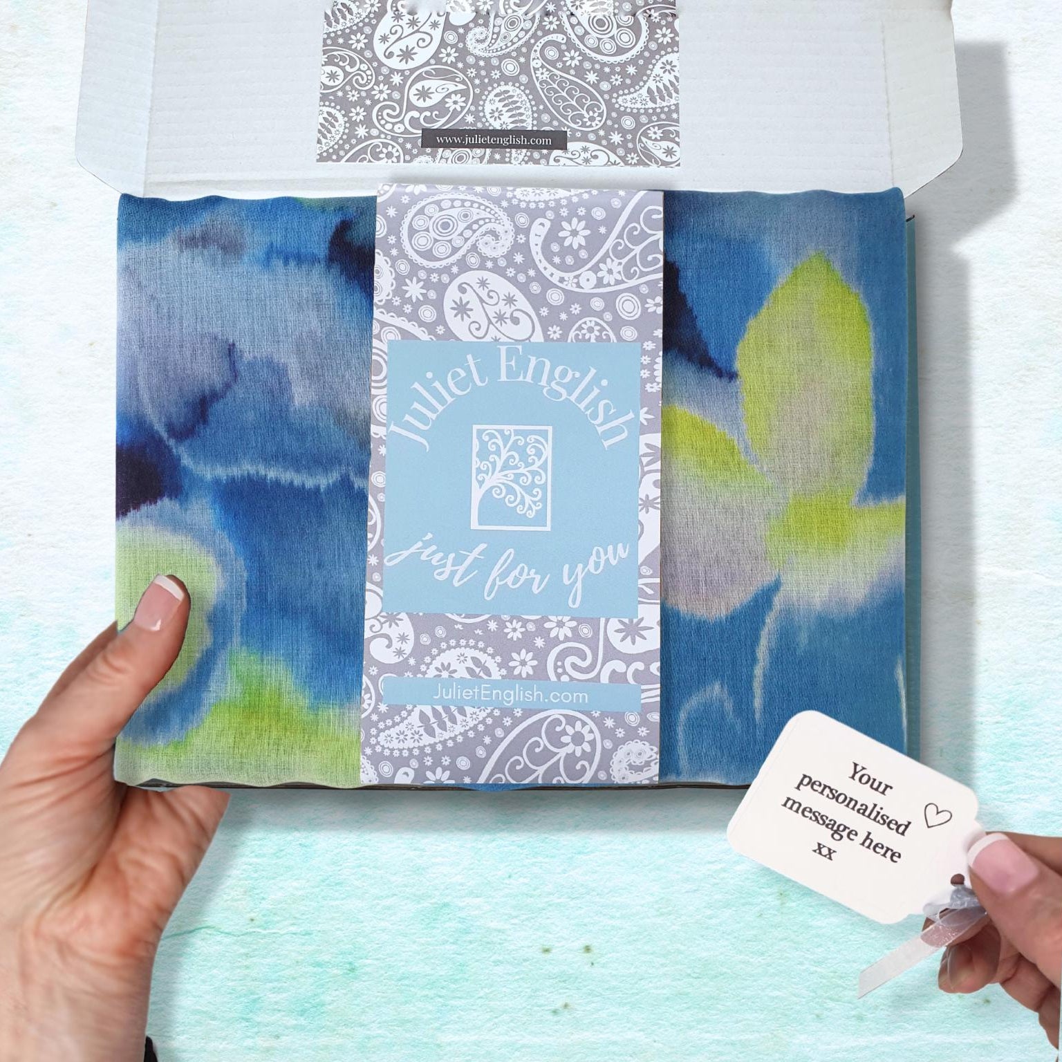 Packaged scarf with a personalised message card on a light blue background