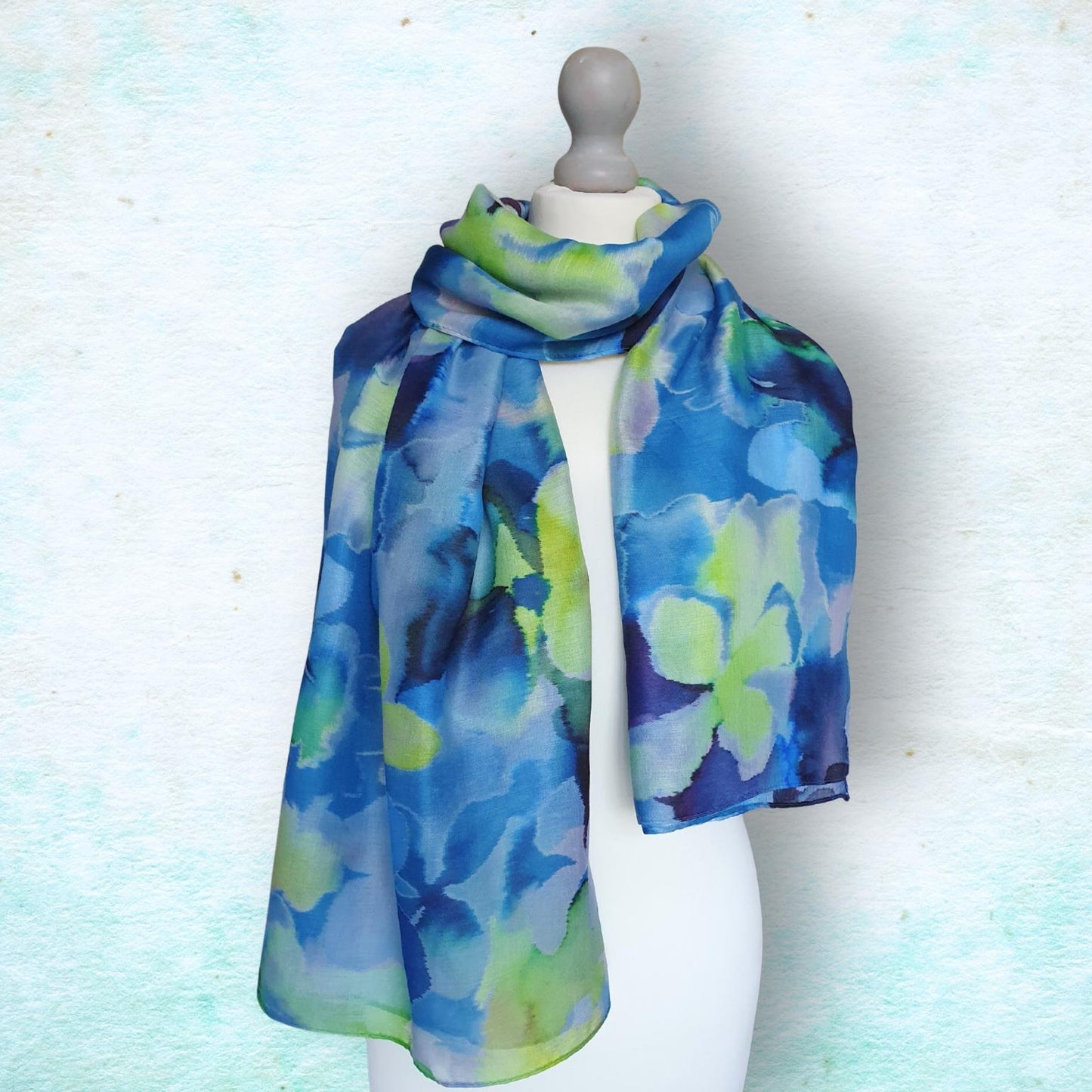 Mannequin wearing a blue and green floral patterned scarf on a light background