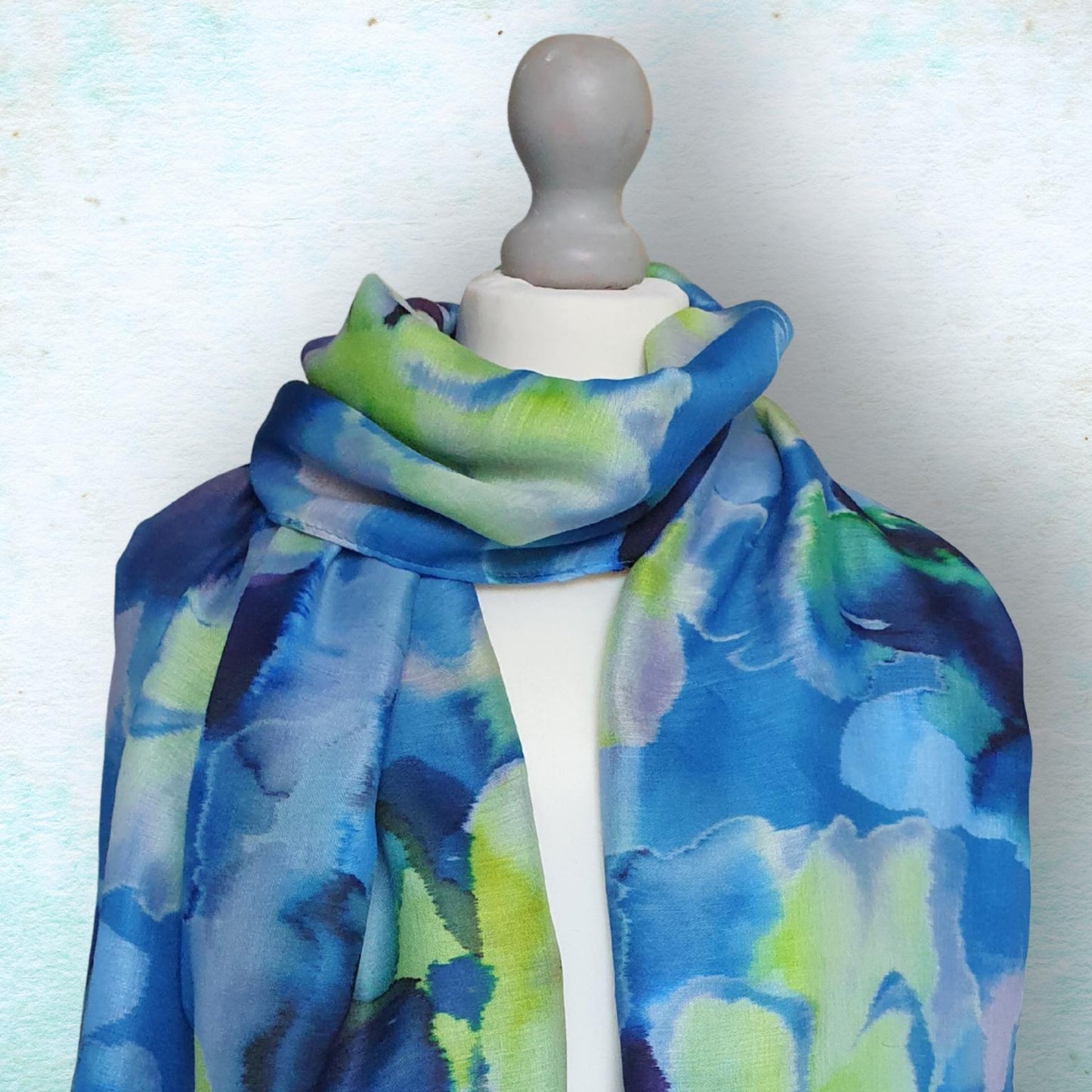 Mannequin wearing a blue and green abstract patterned scarf on a light background