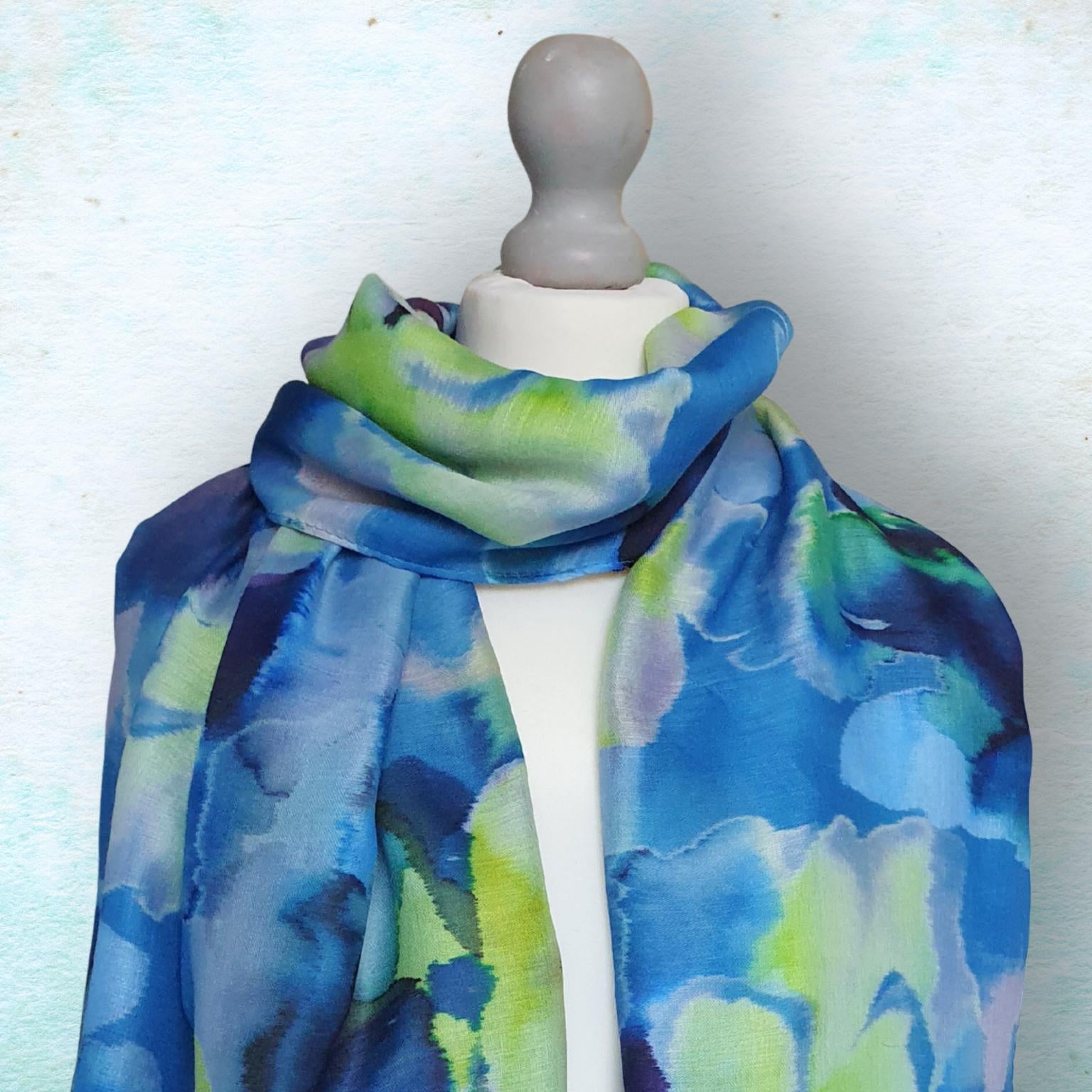 Mannequin wearing a blue and green abstract patterned scarf on a light background