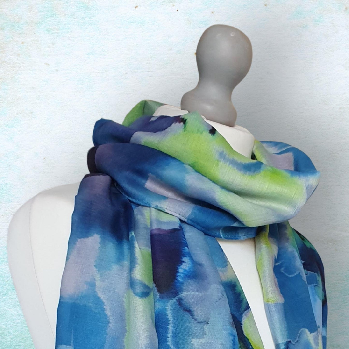 Mannequin wearing a colorful scarf with a blue and green pattern on a light background