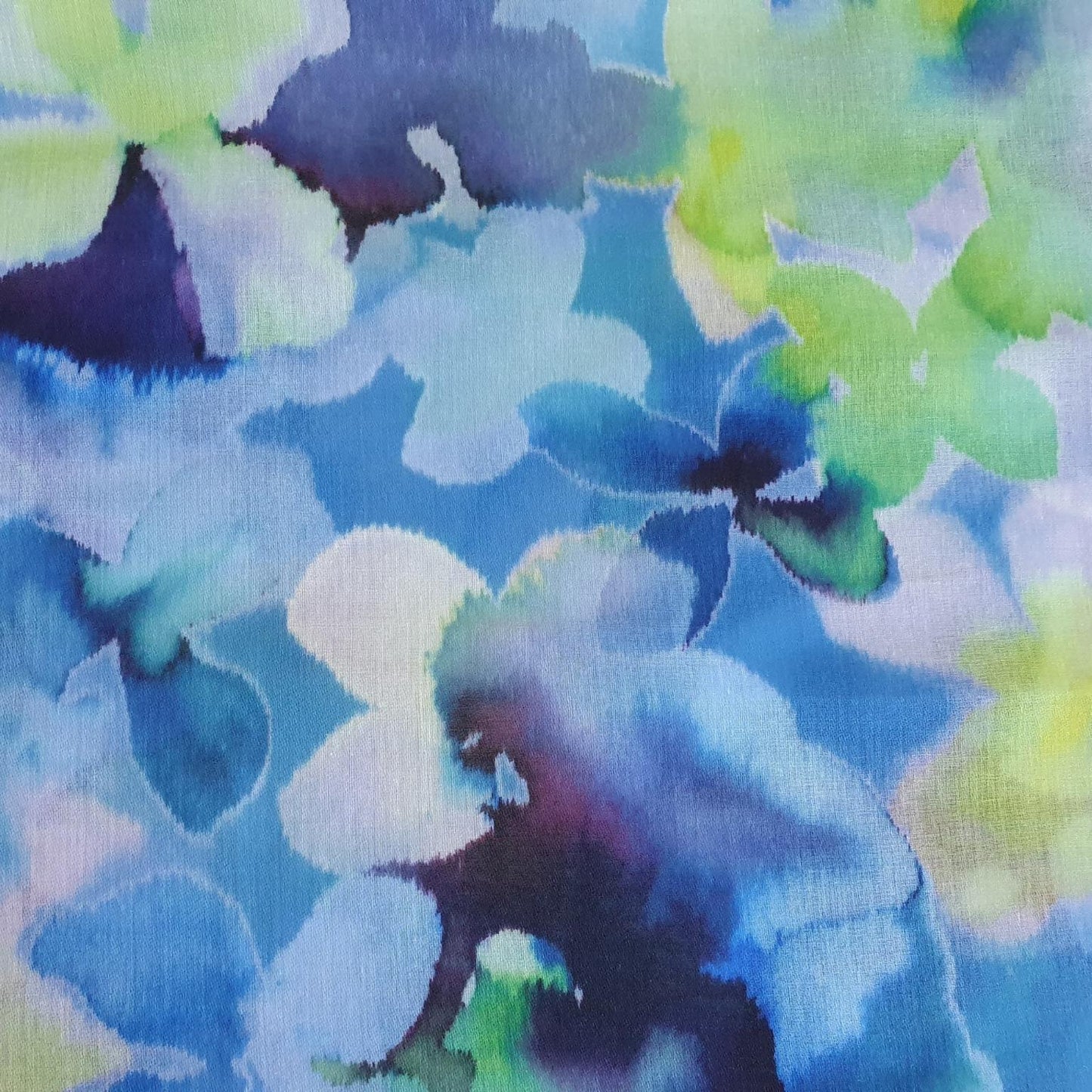 Colorful floral pattern with blue, green, and purple hues on a fabric background.