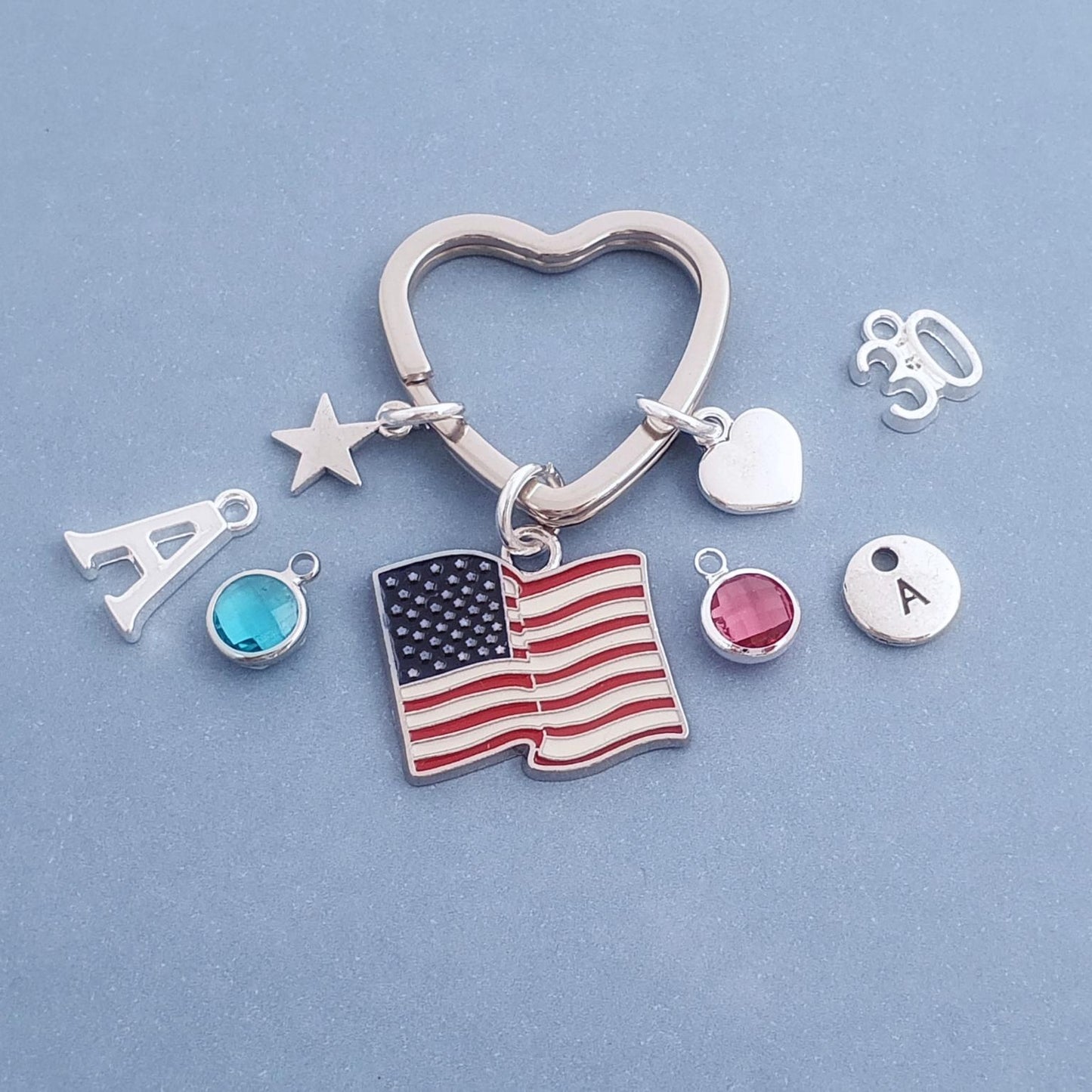 Keychain with various charms including an American flag, Eiffel Tower, and letter 'A' on a blue background