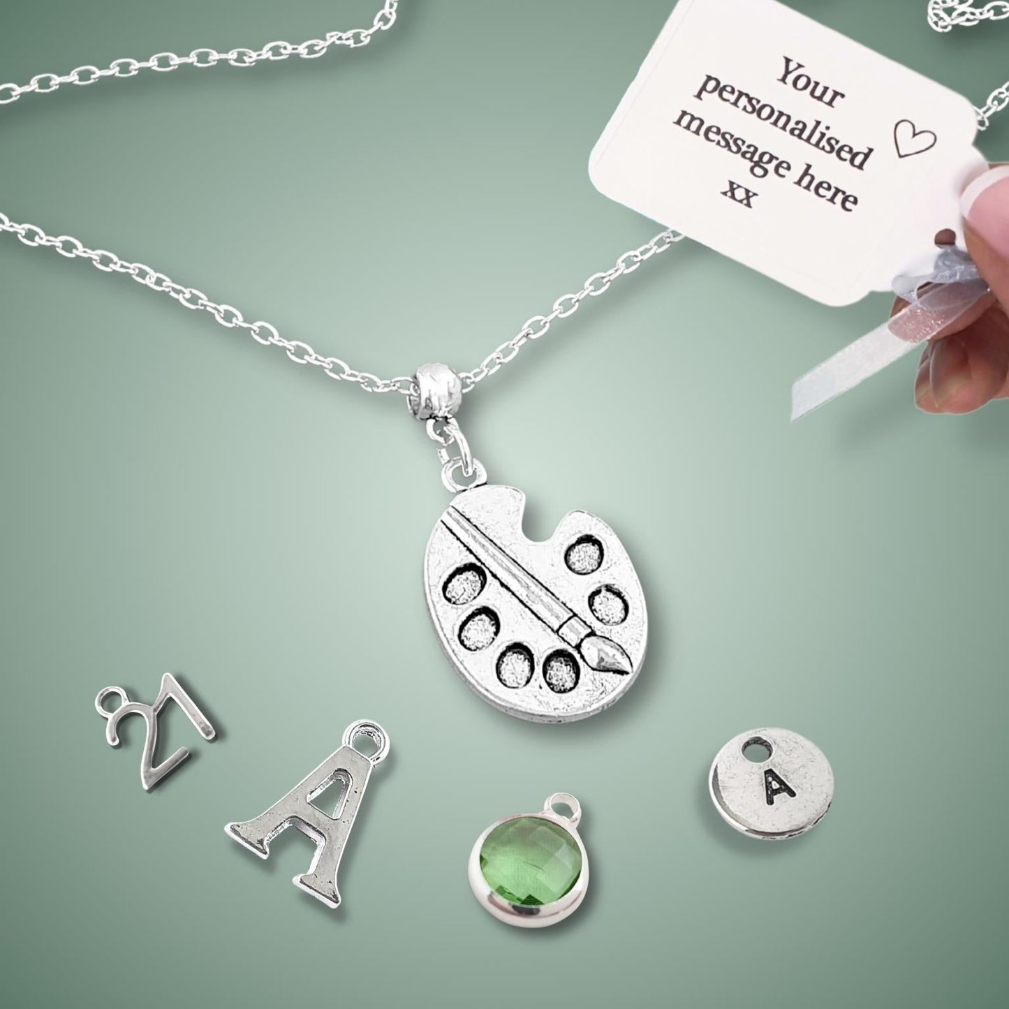 Silver necklace with customizable charms on a green background