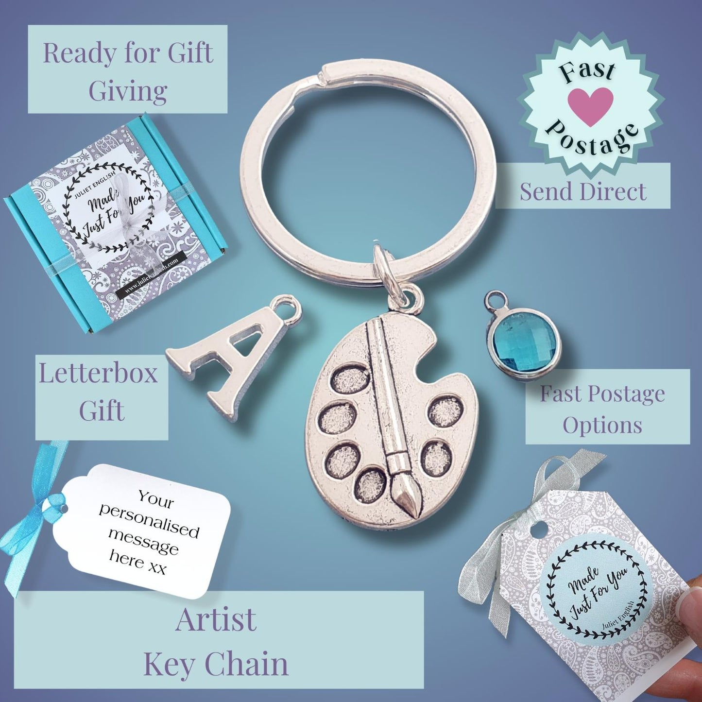An artist keychain gift set displayed on a blue gradient background with text callouts. The set includes a silver-toned oval key ring with a paint palette charm, a small silver letter 'A' charm, a turquoise-blue oval pendant, and a gift tag being held by a hand.