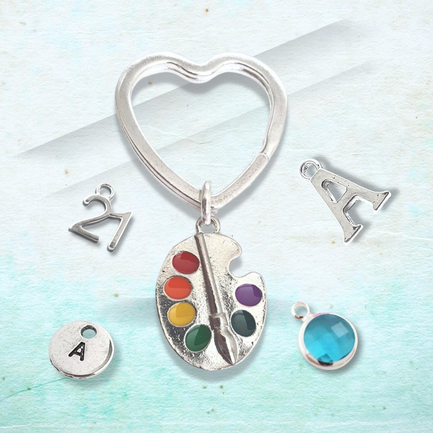 Silver keychain with heart-shaped design and various charms on a light blue background